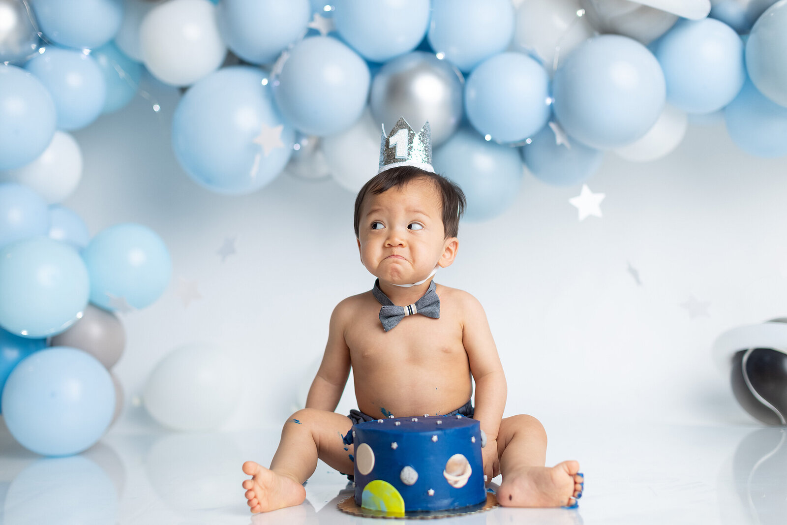 Baby making funny face and space themed cake smash.