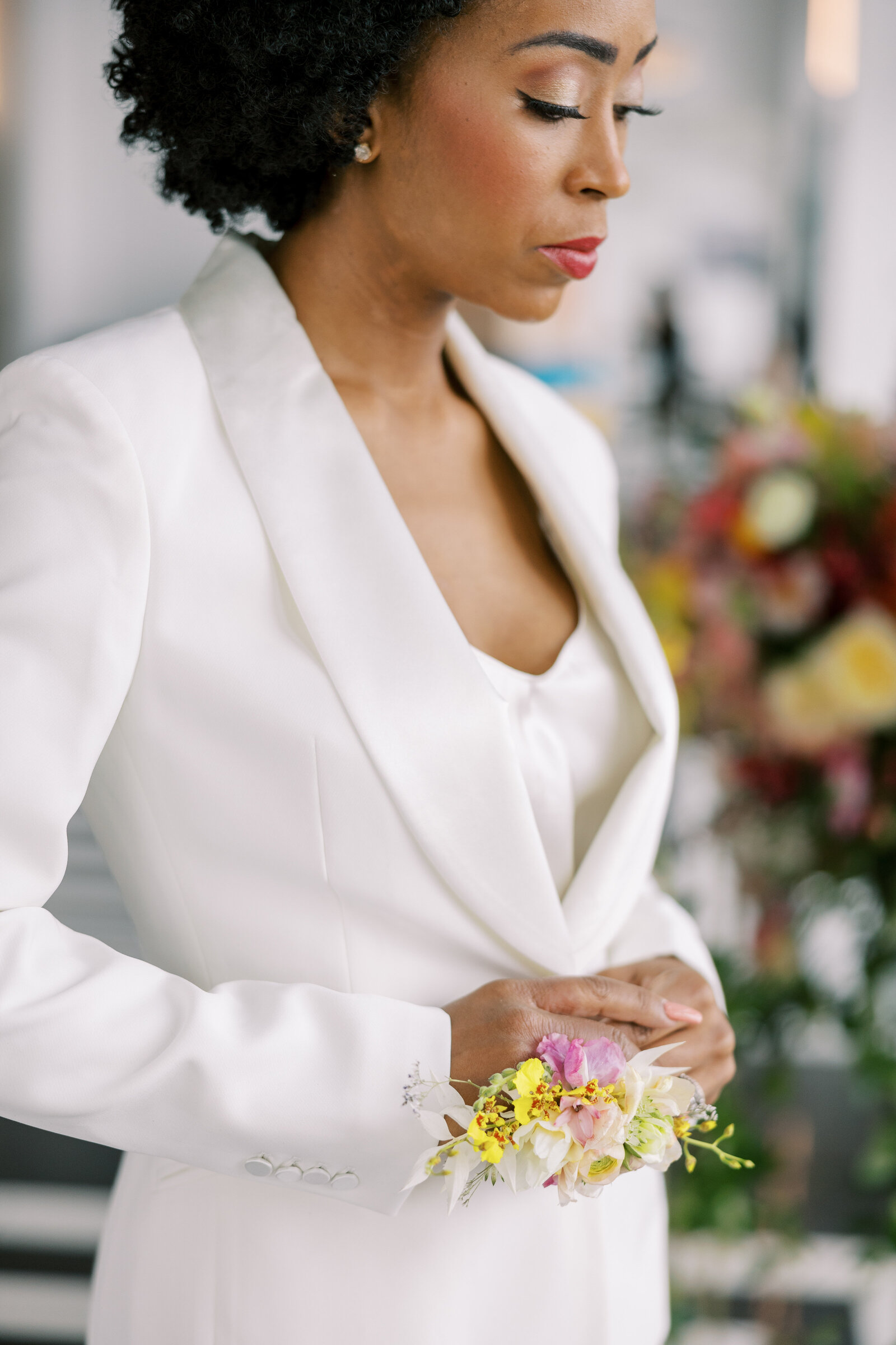 Bride in white jacket with colorful flowers on wrist