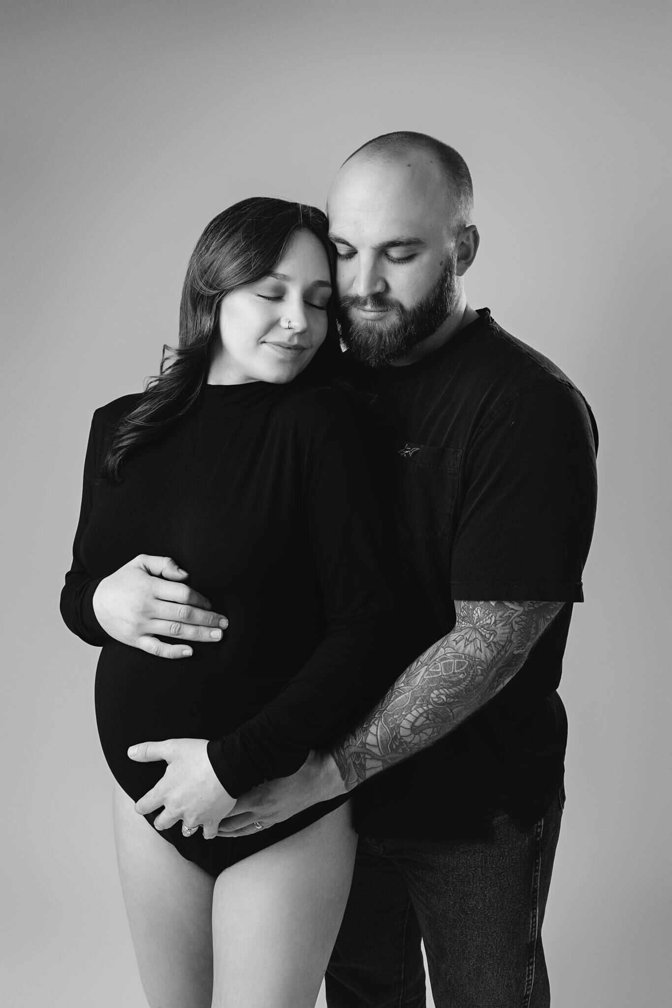 expecting couple are hugging each other and touching her belly in a soft and romantic way for their maternity photoshoot
