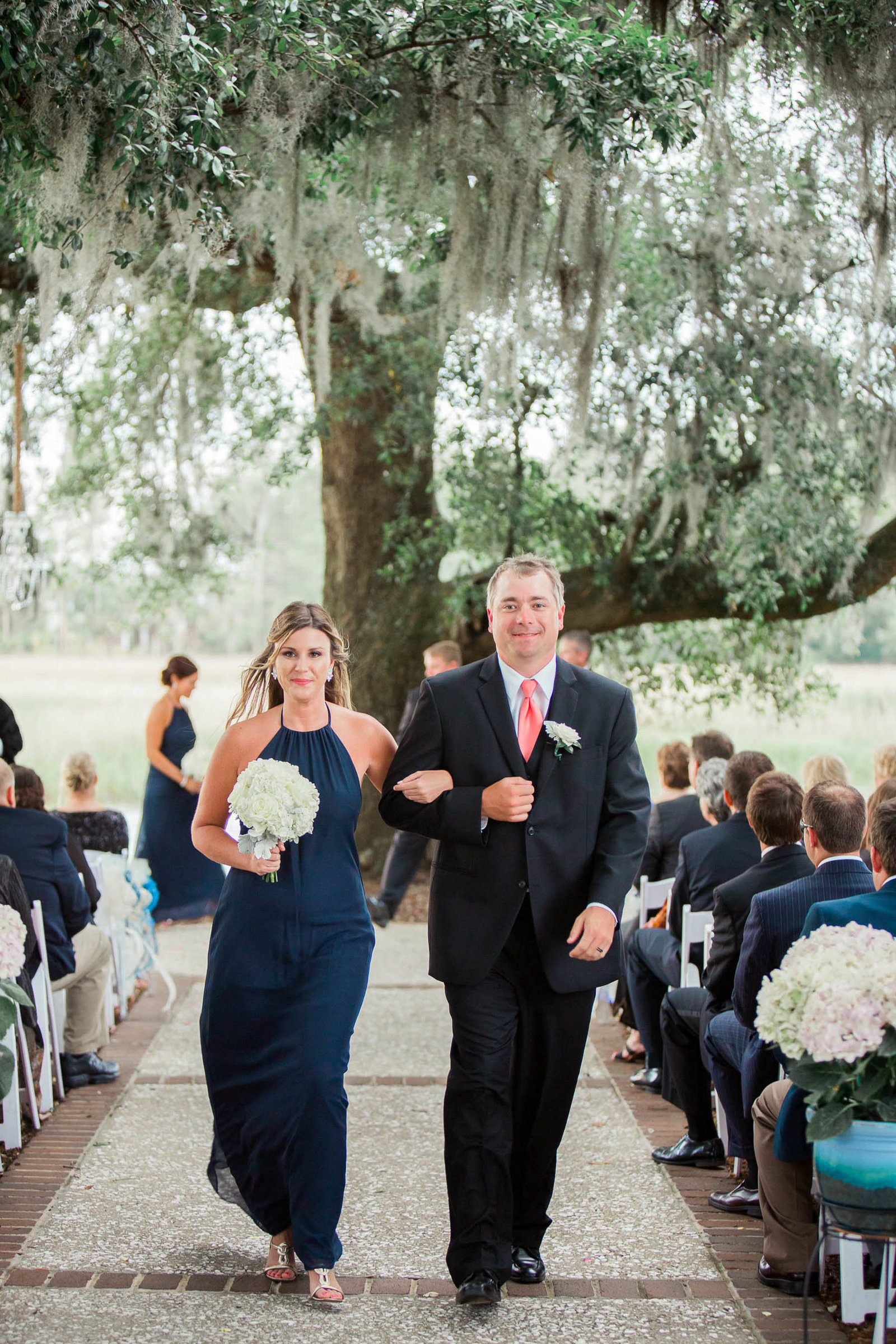 Bridesmaid and groomsman walk down the aisle, Dunes West Golf and River Club, Mt Pleasant, South Carolina