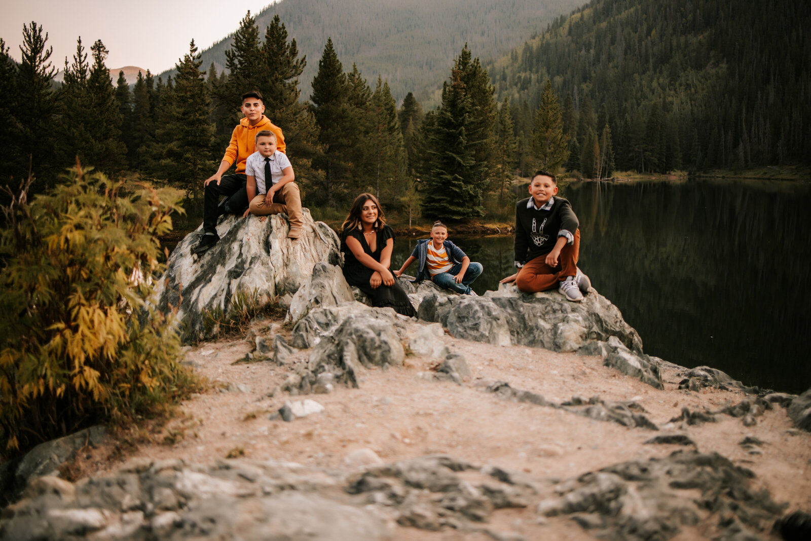 family children sitting on rocks in vail colorado with a lake behing them