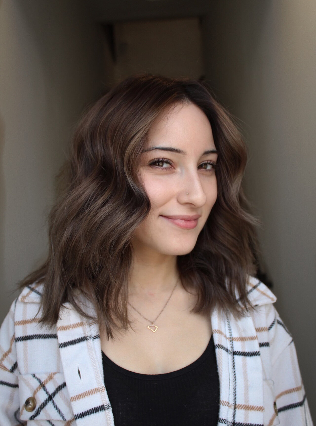 Woman with a brunette balayage lob smiling in salon environment