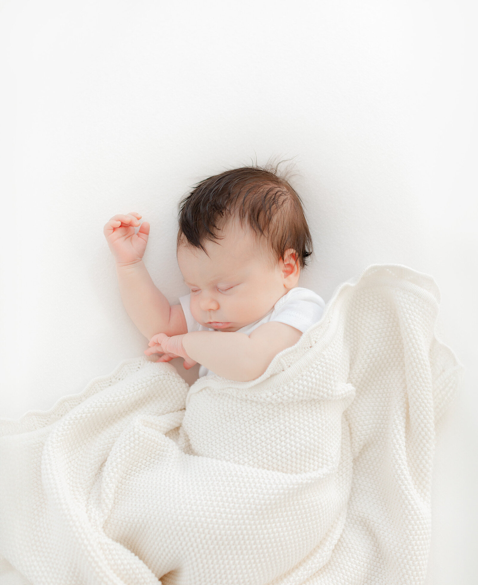 sleeping newborn wrapped loosely in textured blanket