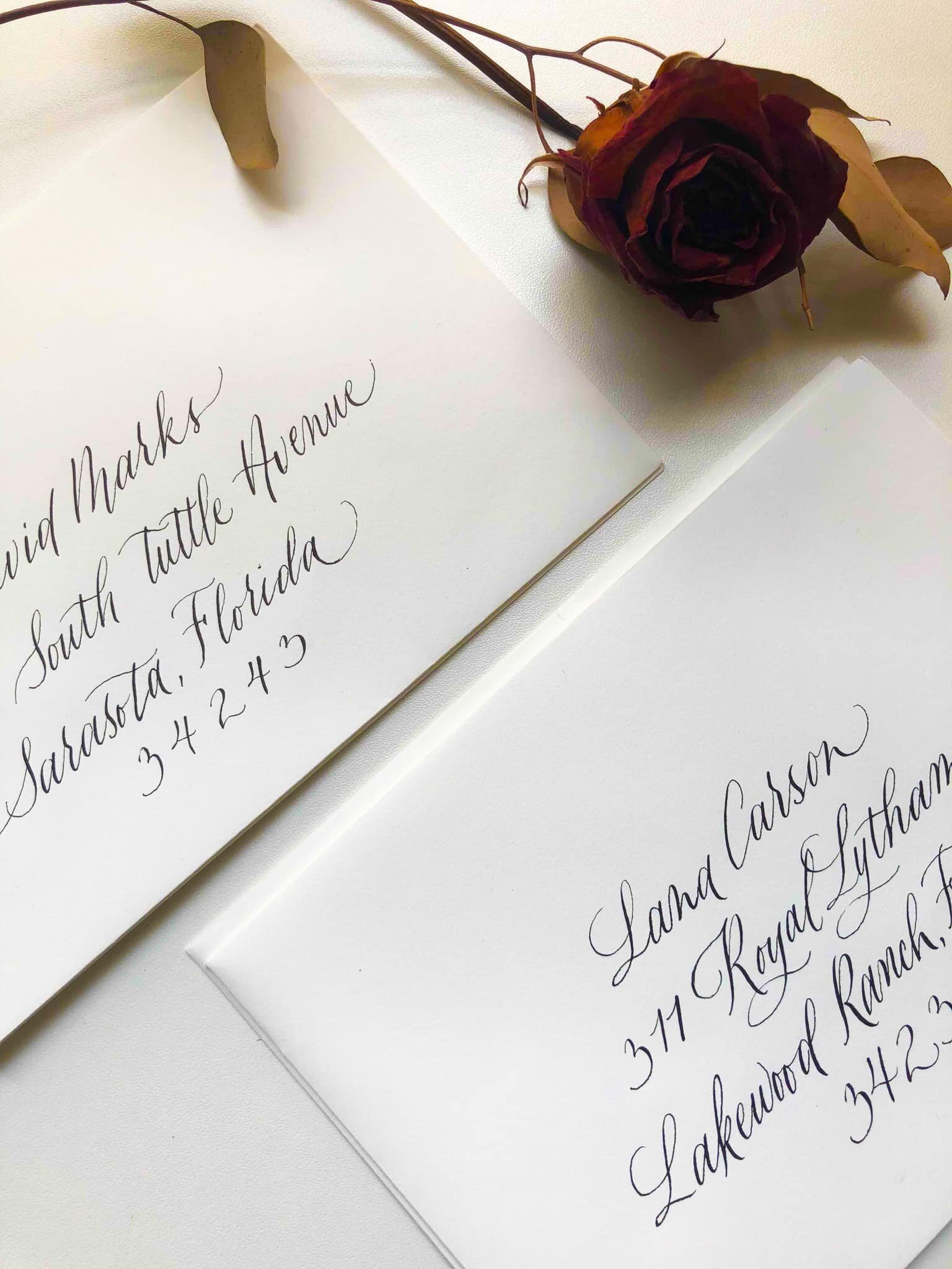 stack of two envelopes with a dried rose in copperplate calligraphy