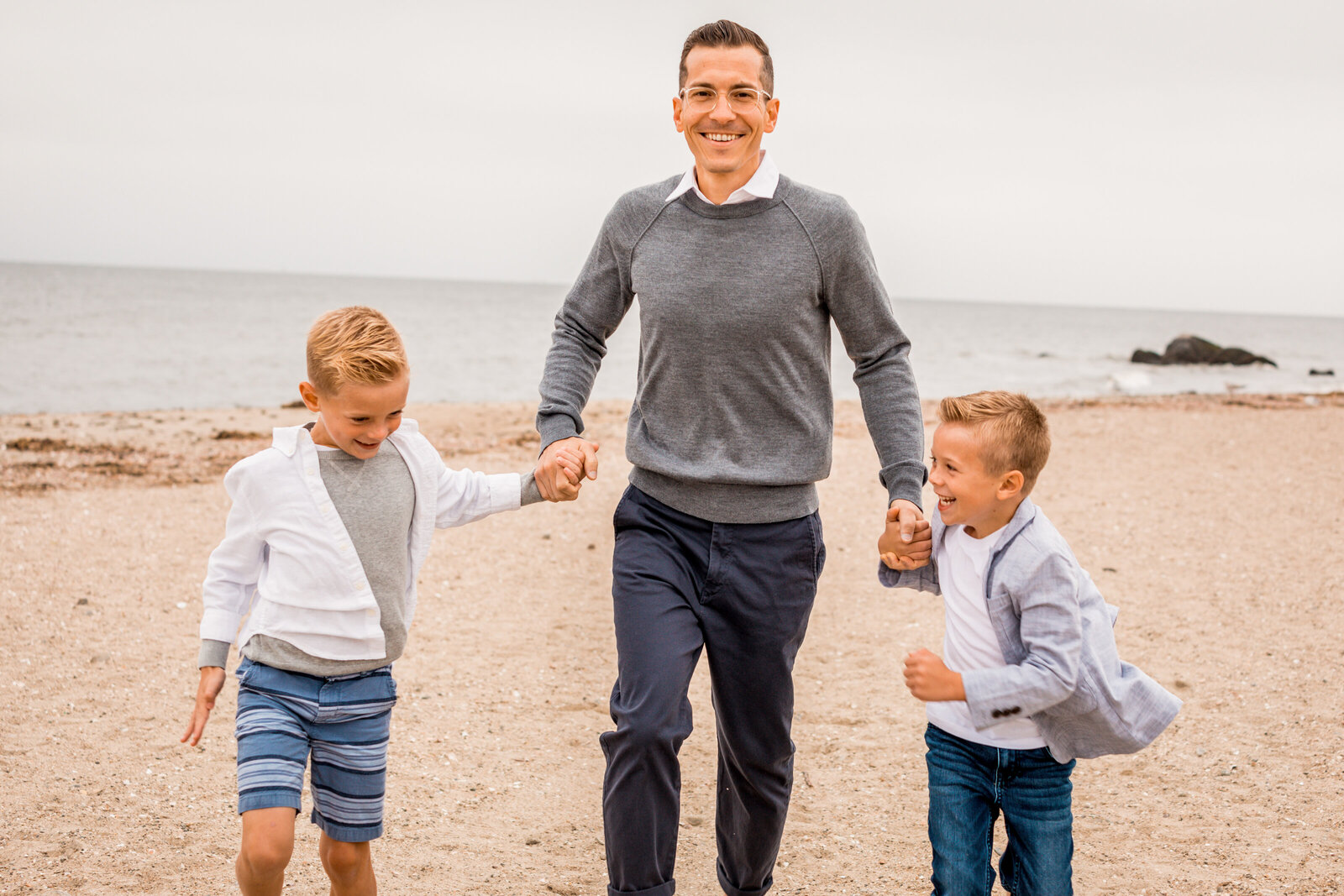 dad is running with his boys on the beach