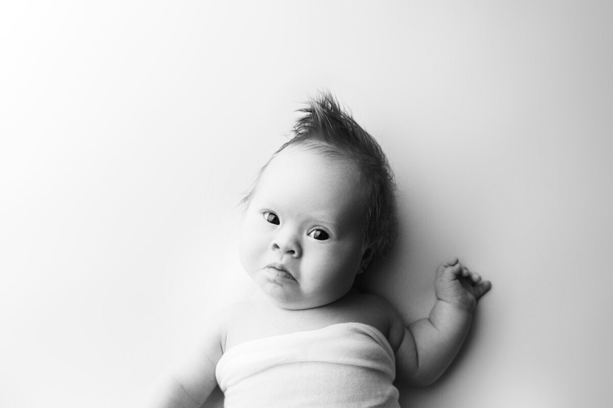 Newborn baby looking at new jersey newborn photographer on bed