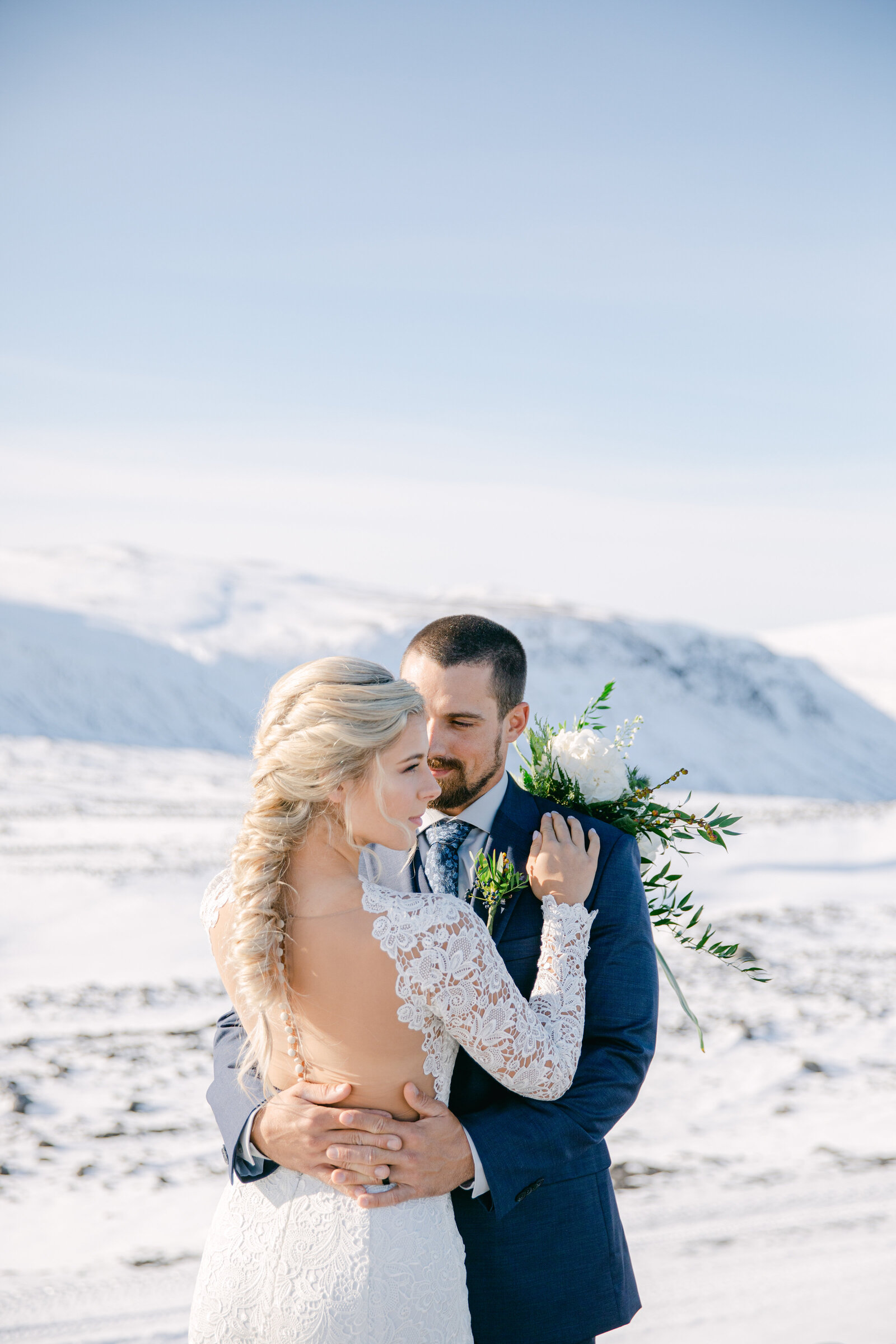 bride and groom face each other in iceland terrain with snow and rock all around them