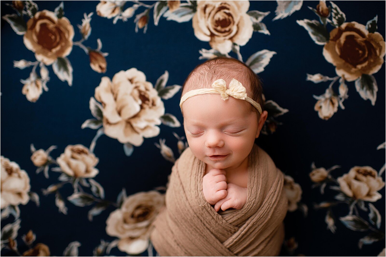 newborn on navy and brown floral blanket