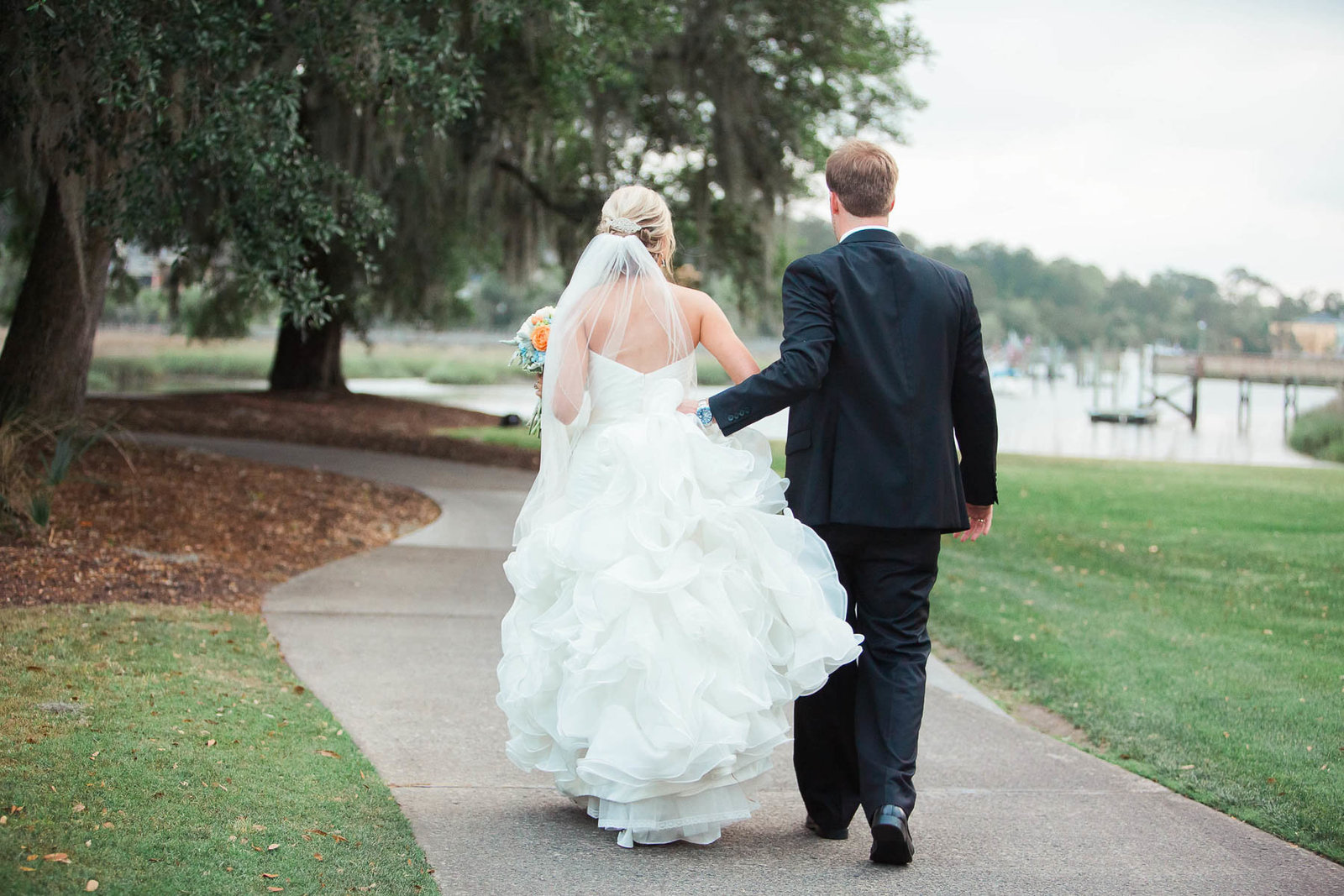 Bride and groom walk in field, Dunes West Golf and River Club, Mt Pleasant, South Carolina