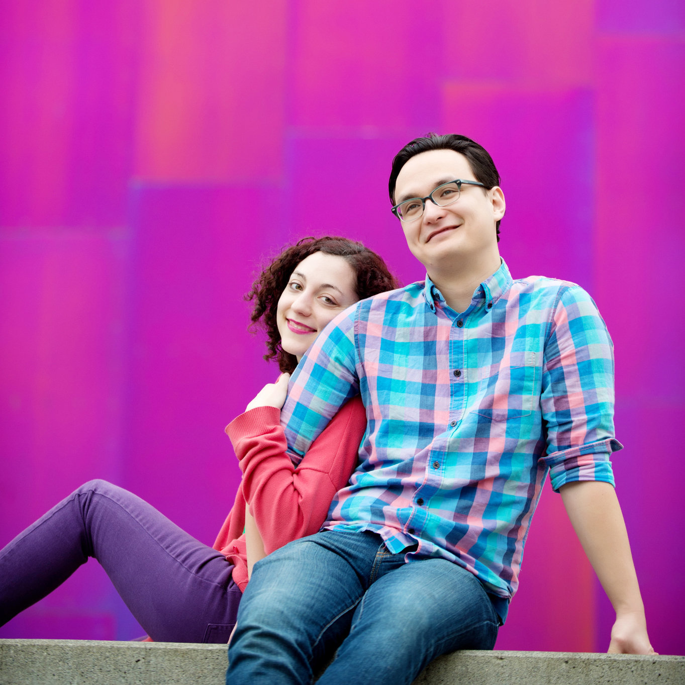 a man laughs as a woman leans on his arm in front of the pink museum of pop culture in seattle
