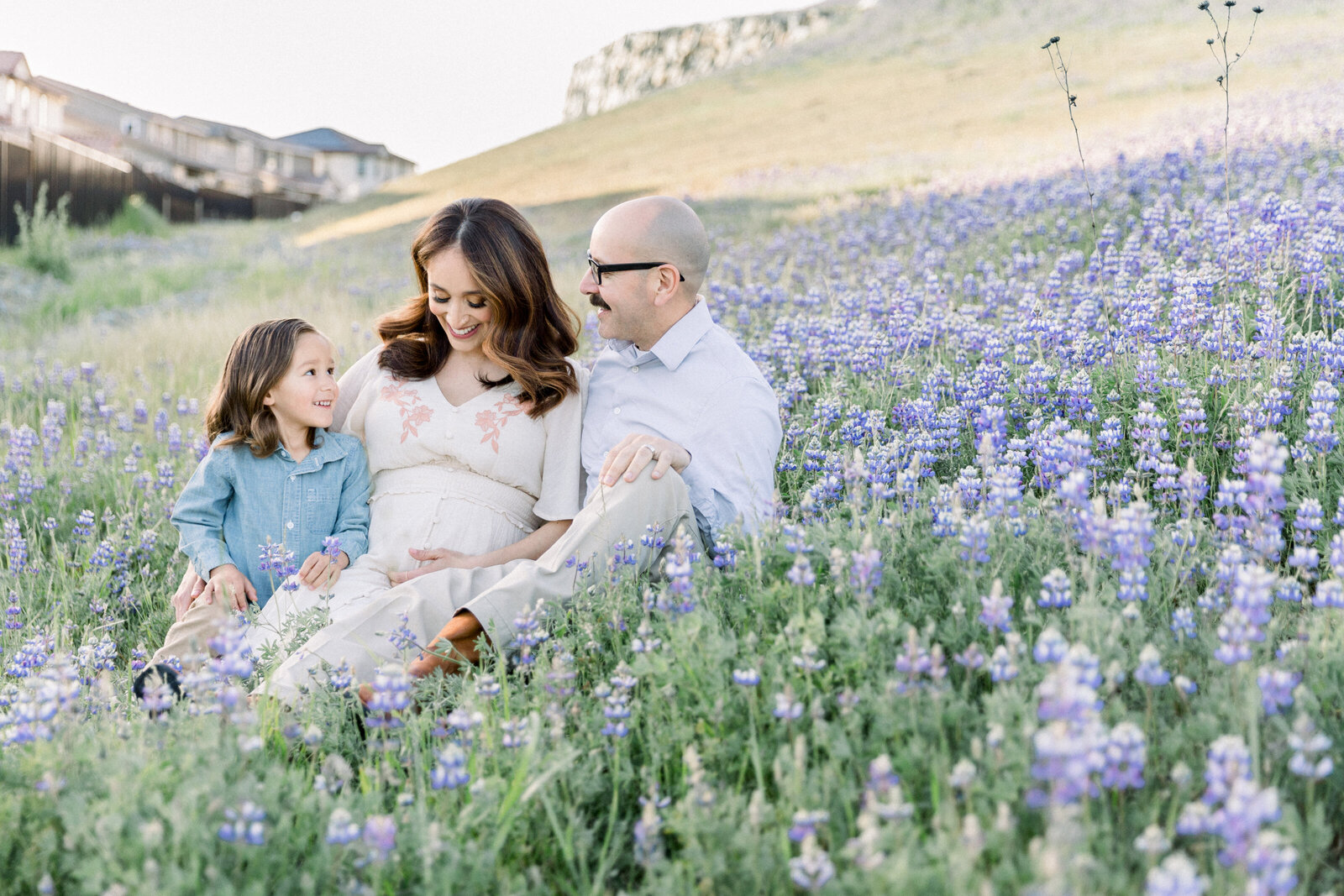 Family of three with baby on the way sitting in wildflowers together taken by Family Photographer Sacramento Kelsey Krall