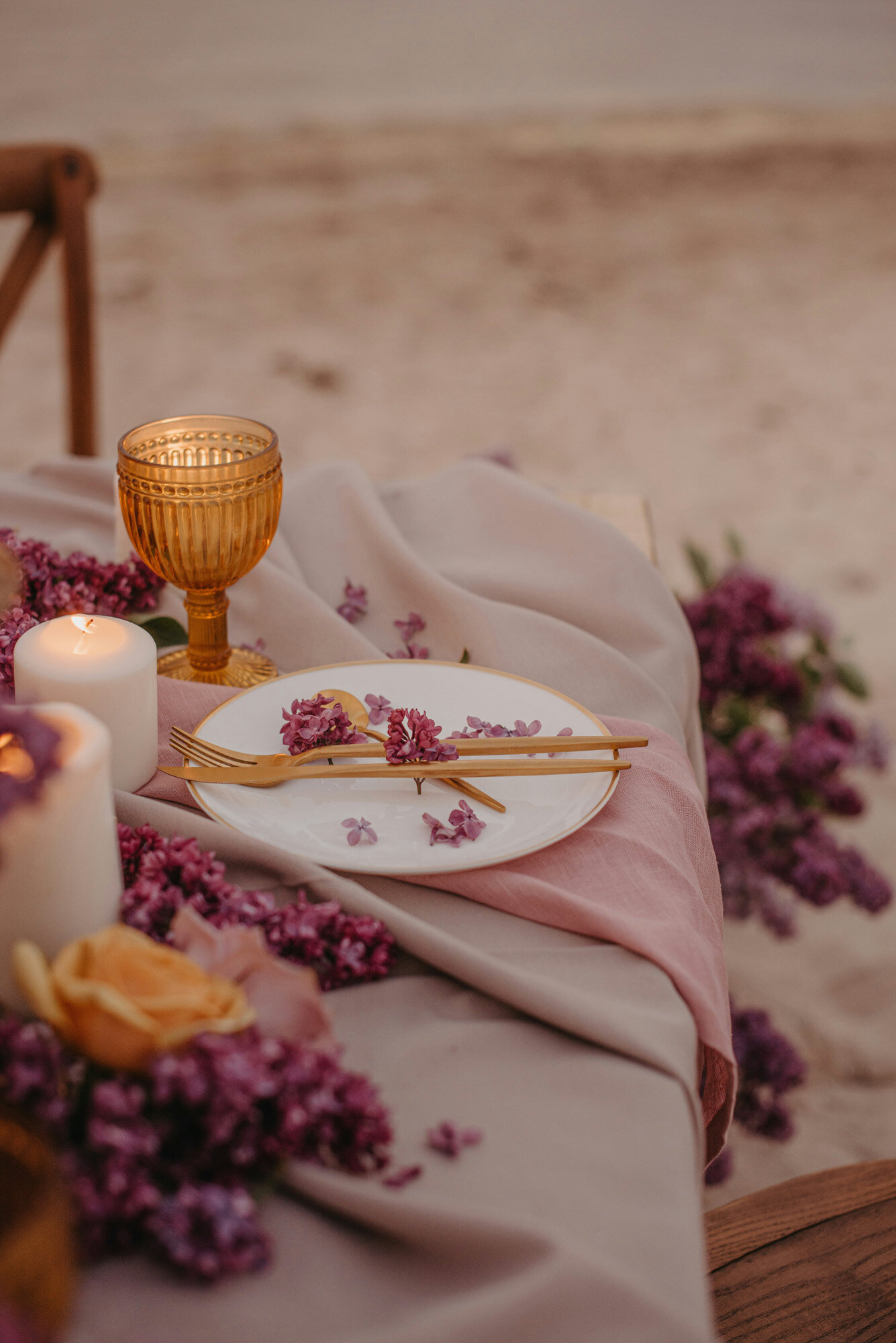 Table with purplish cloth, dinnerwares, glass and lighted candle