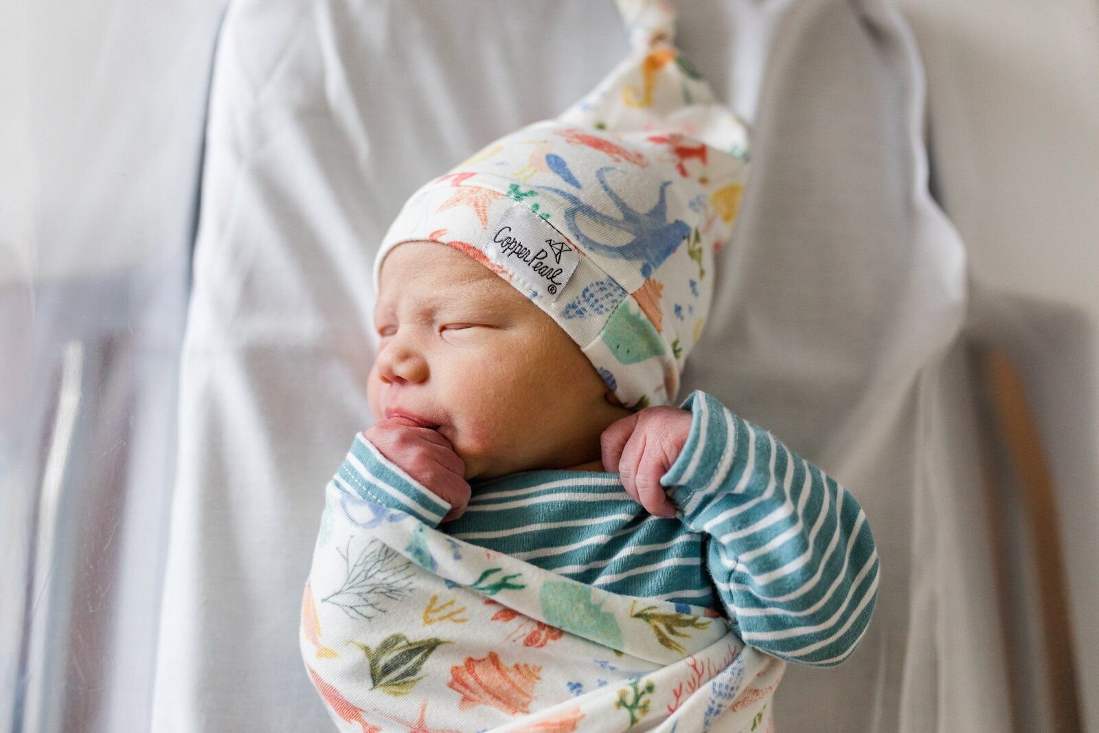 Newborn boy photo during fresh 48 newborn  session  in hospital. He's wearing Copper Pearl brand Nautical swaddle and hat.
