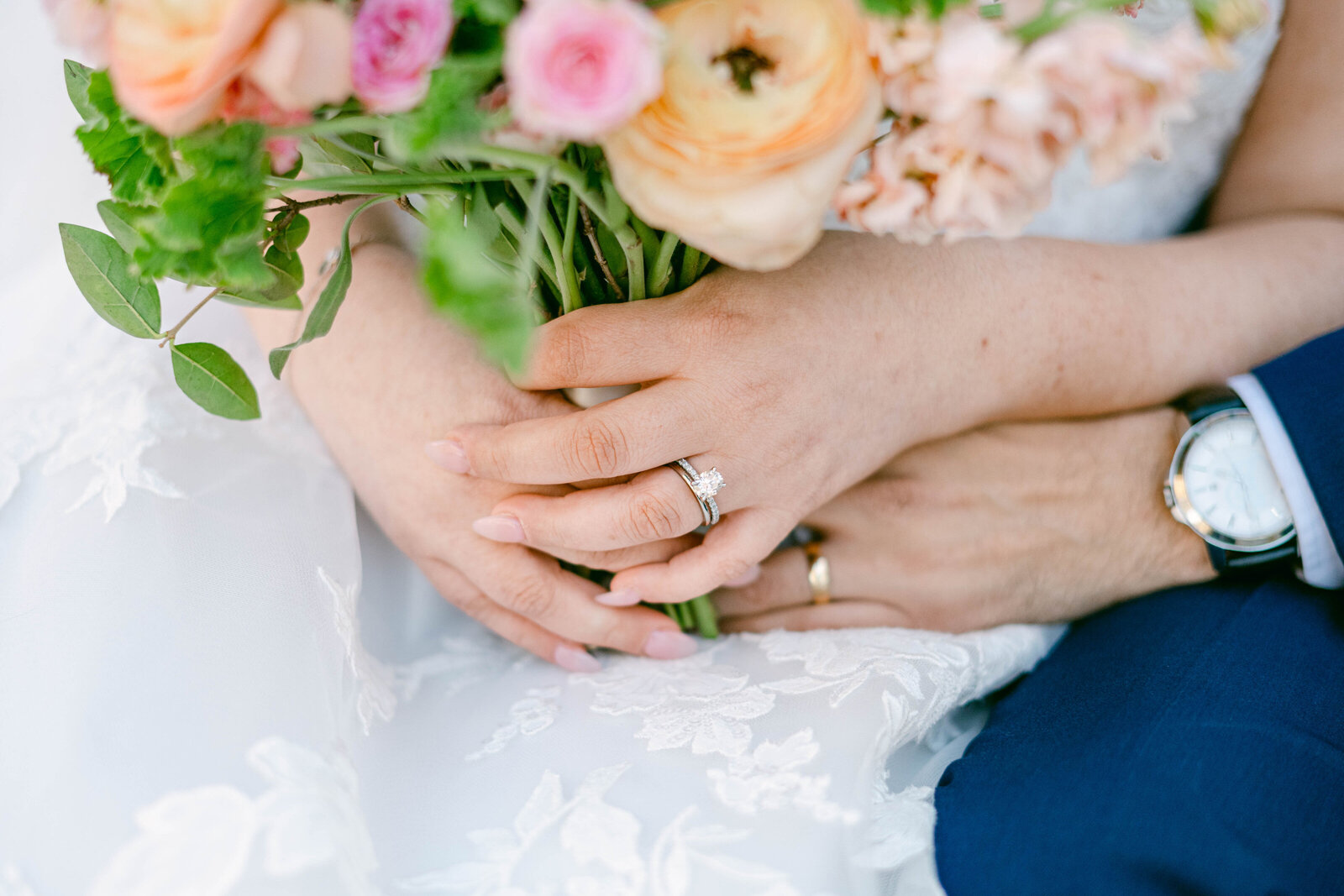 Hand holding wedding rings with colorful bouquet