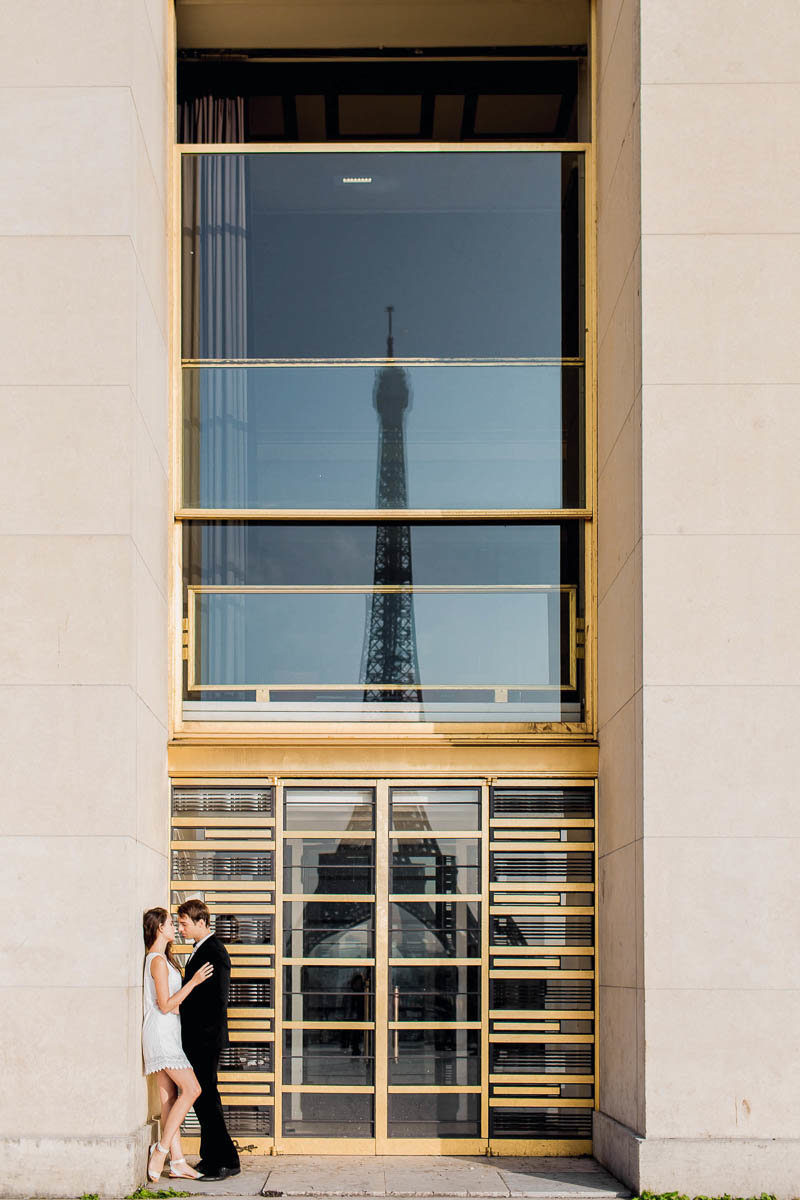 Bride and groom snuggle with the Eiffel Tower reflected in the glass, Paris, France