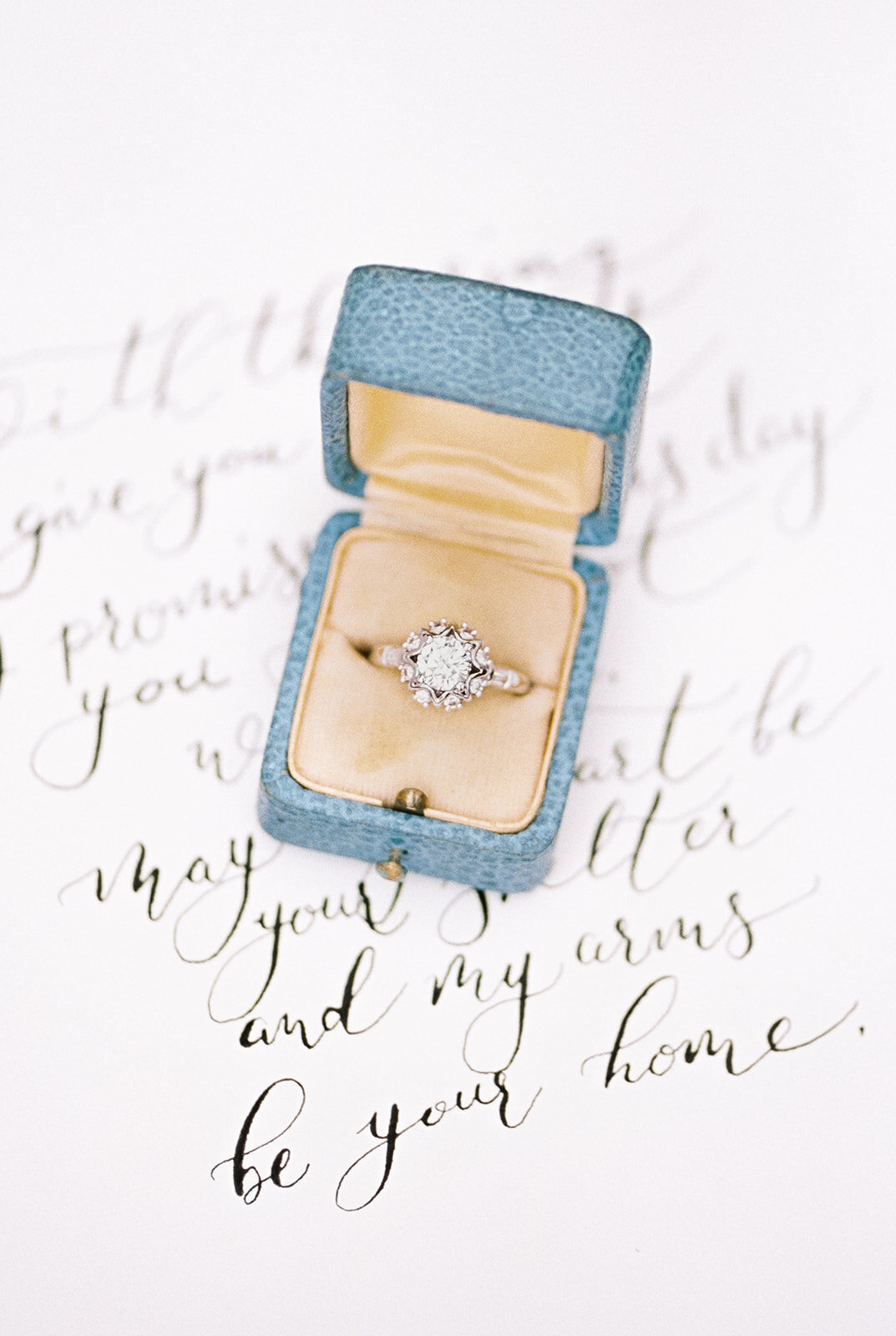 Blue and yellow antique ring box on calligraphy love letter at Cottage at Riverbend Wedding by the Best Boise Wedding Photographers