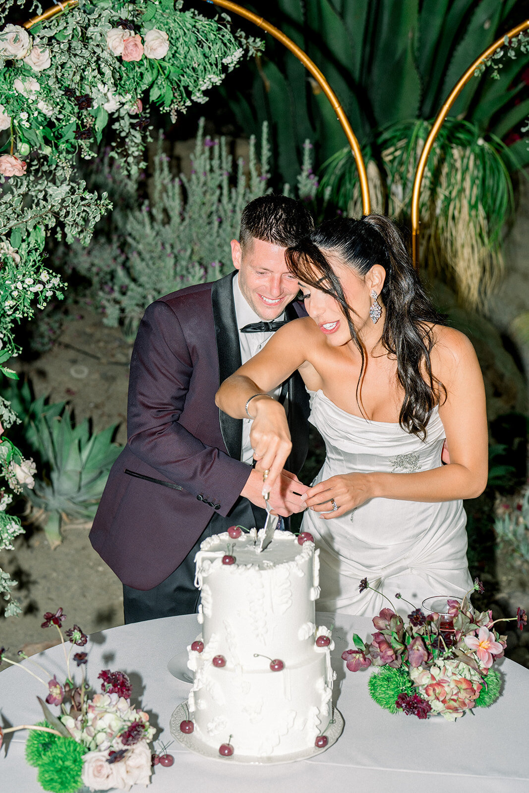Bride and groom laugh while cutting the wedding cake at their luxury Hummingbird Nest Ranch reception, captured in candid documentary style.