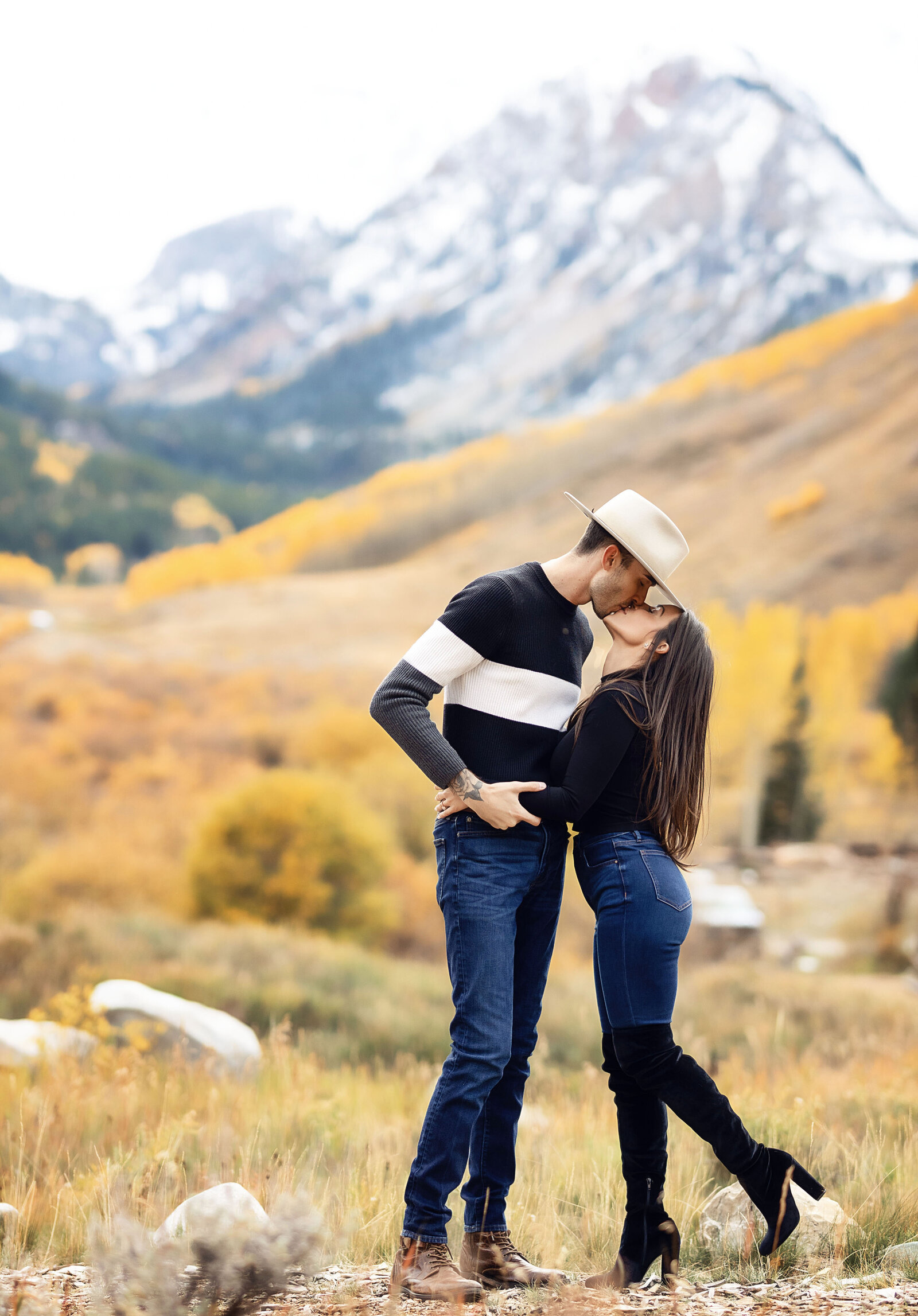 A cute couple kisses with Aspen mountains as the backdrop during their Aspen engagement photoshoot.