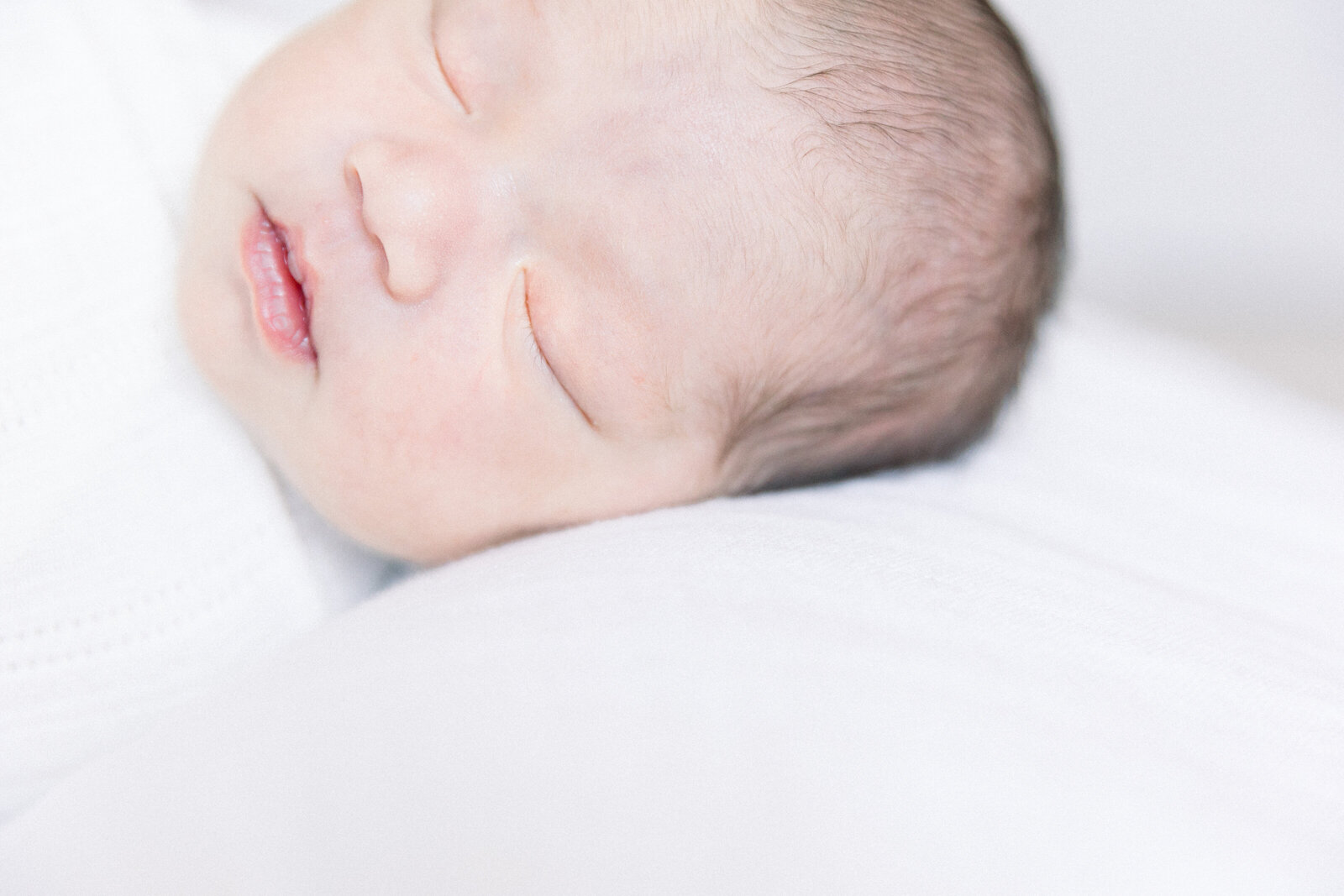 Image of sleeping baby's face close up on white pillow taken by Sacramento Newborn Photographer Kelsey Krall Photography