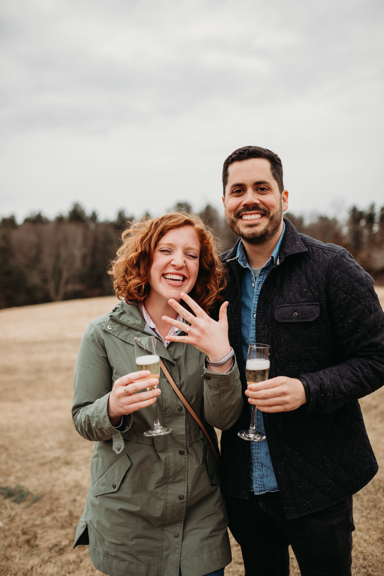 couple laughs as they show their engagement ring