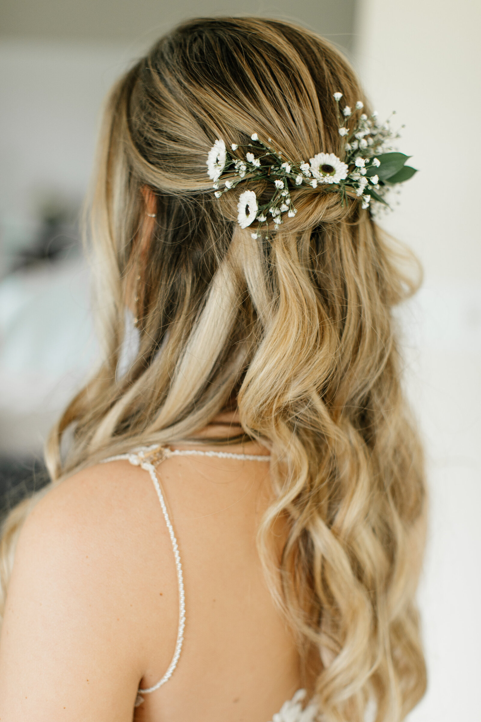 Blonde-haired bride turned to  show only her bridal hair with flowers.