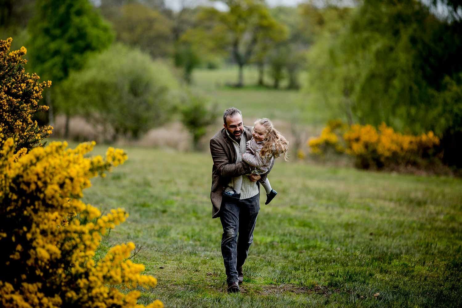 dad running through a bristol park holding his daughter