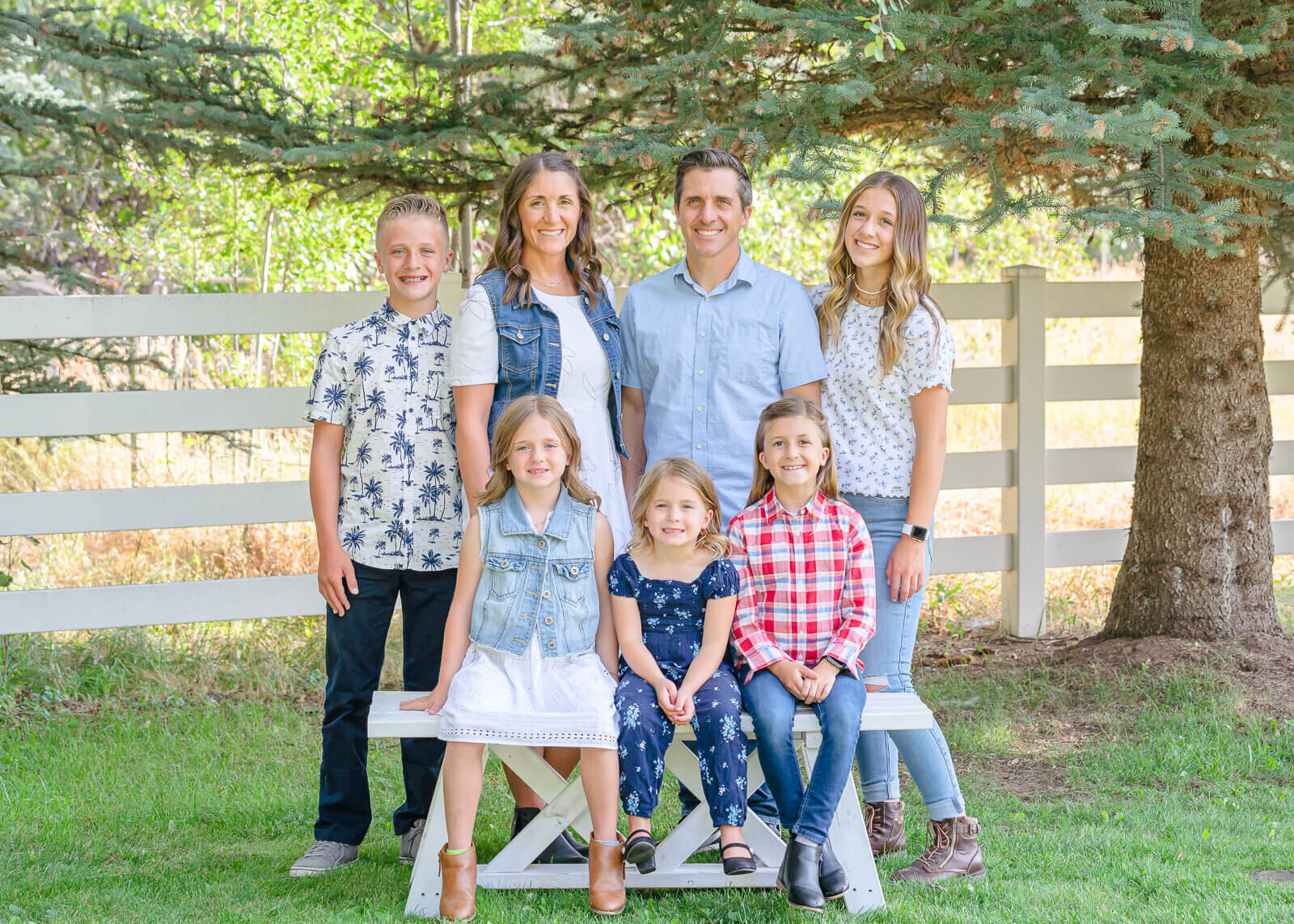 A mother, father, and their two boys and three girls pose for the camera during their family portrait session at a farm in Huntsville. Captured by Salt Lake Family Photographer Melissa Woodruff photography