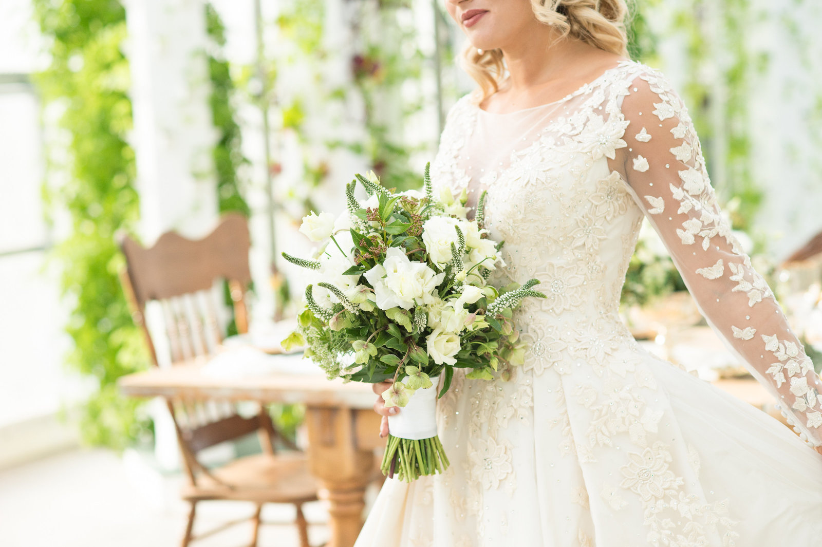 Beautiful bride in room of greenery holding bouquet