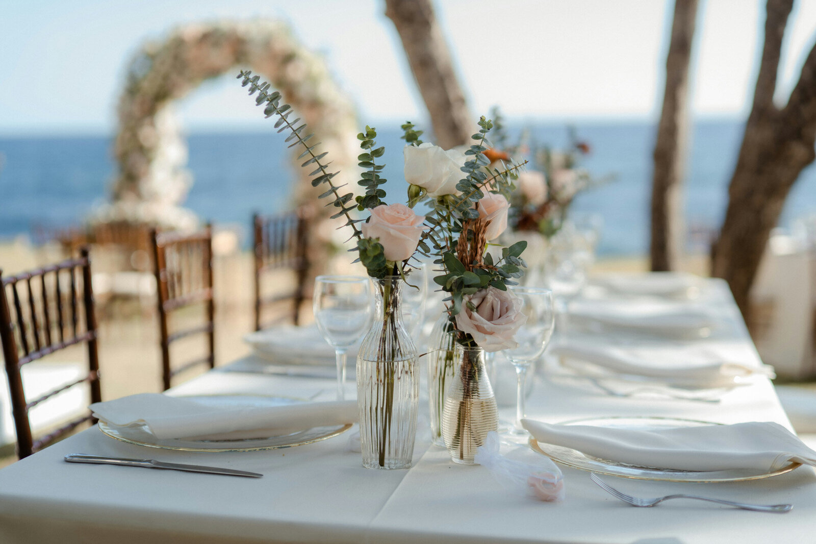 Floral centerpiece in a transparent glass with beach view behind