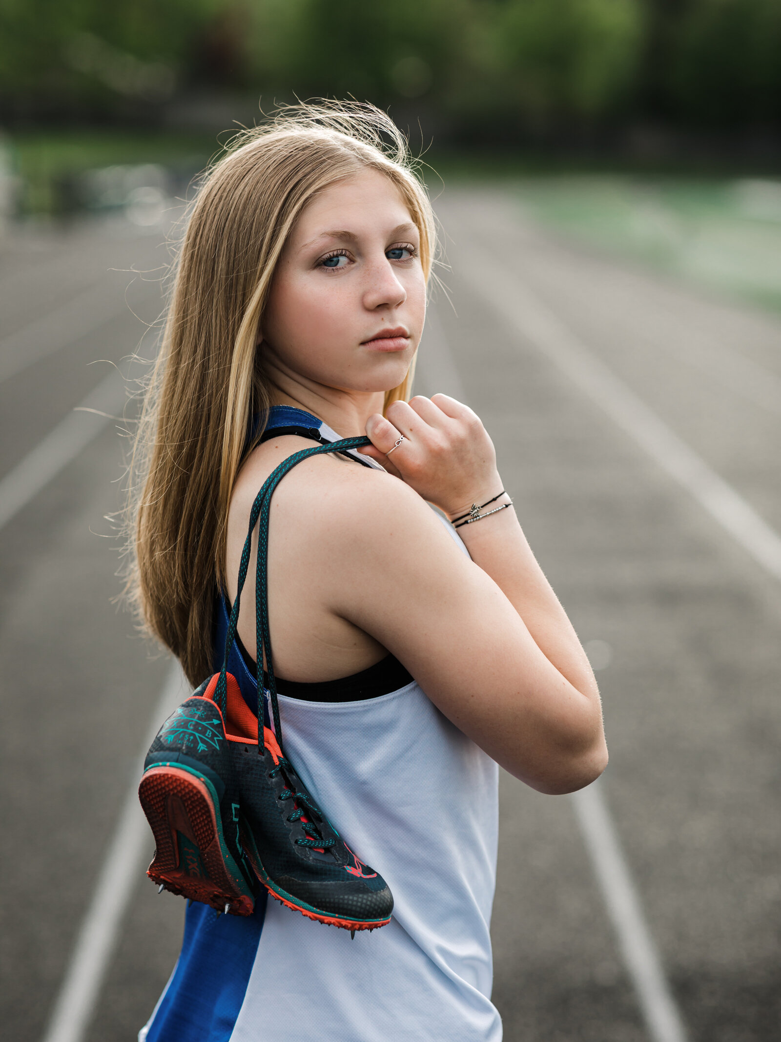 girl holding track shoes on field for senior portraits