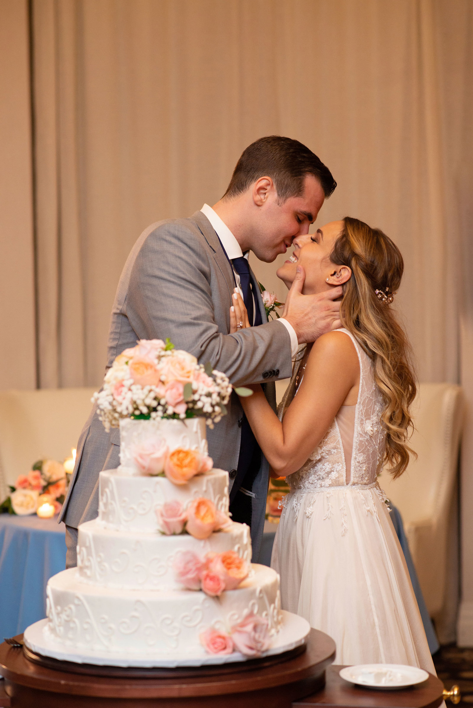 Bride and groom kissing in front of cake at Atlantis Banquet and Events