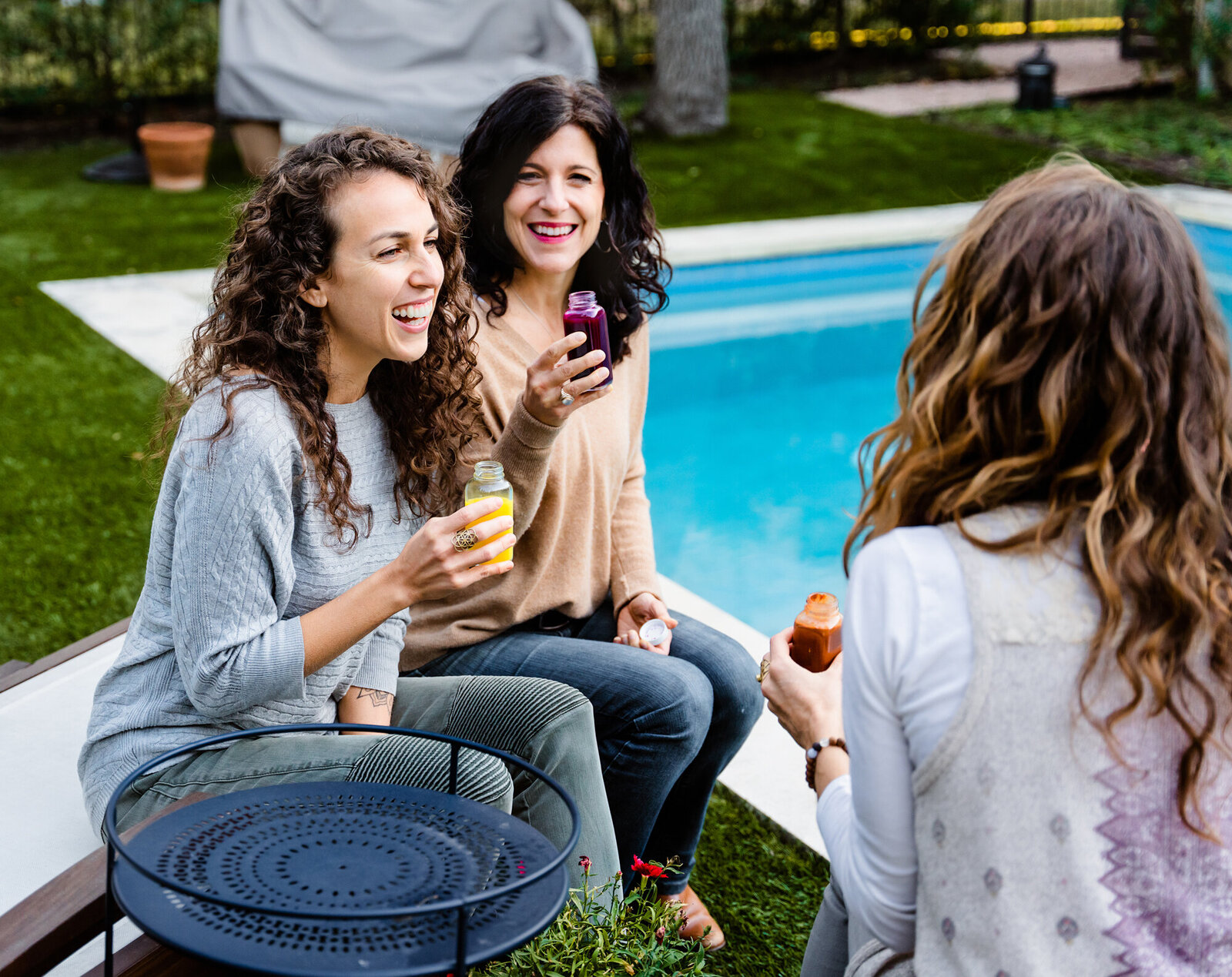 Branding Photographer, three woman enjoy drinks in the grass near the pool