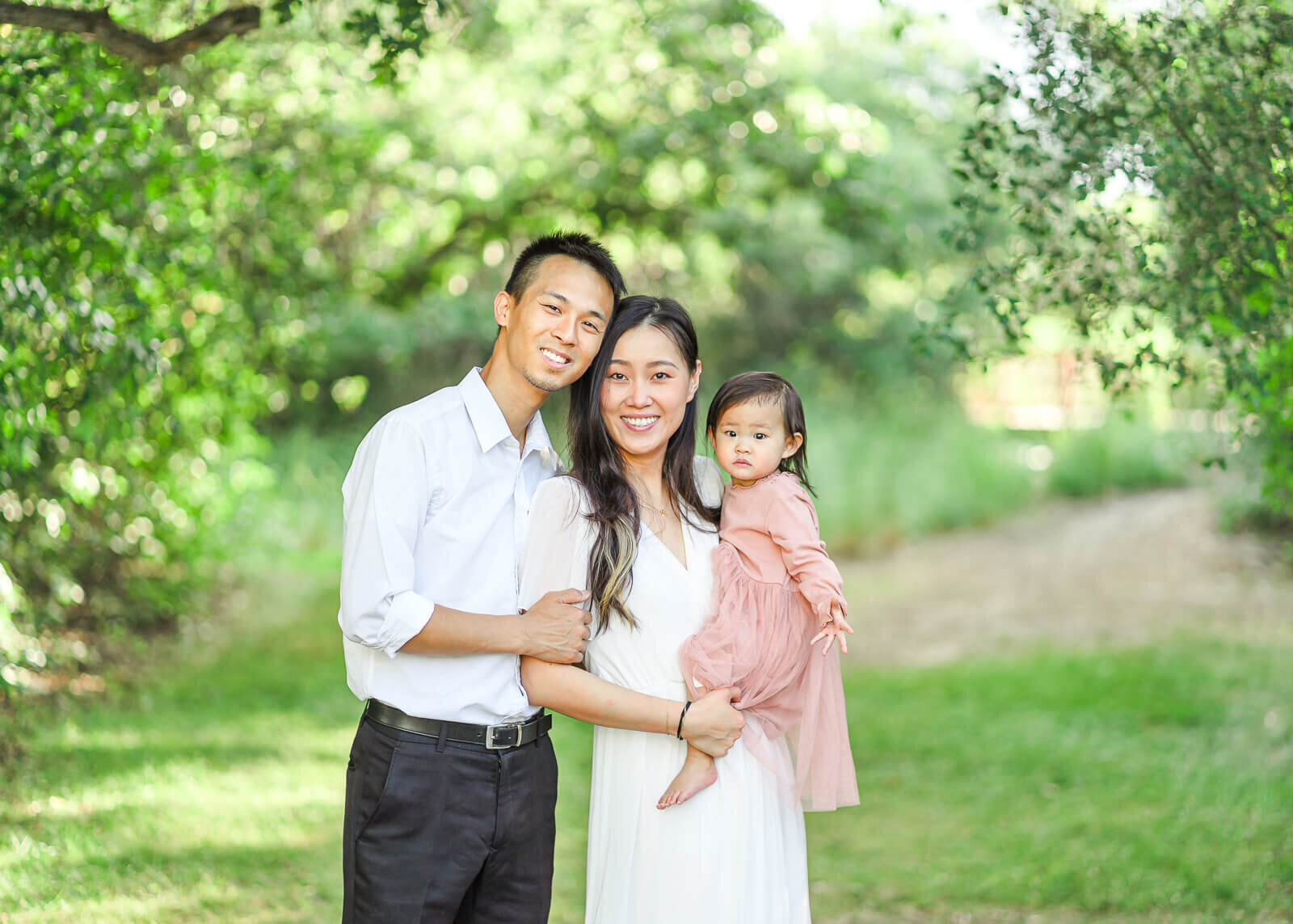 A father and mother hold their baby daughter for portraits. Captured at Highland Glen Park by Melissa Woodruff Photography