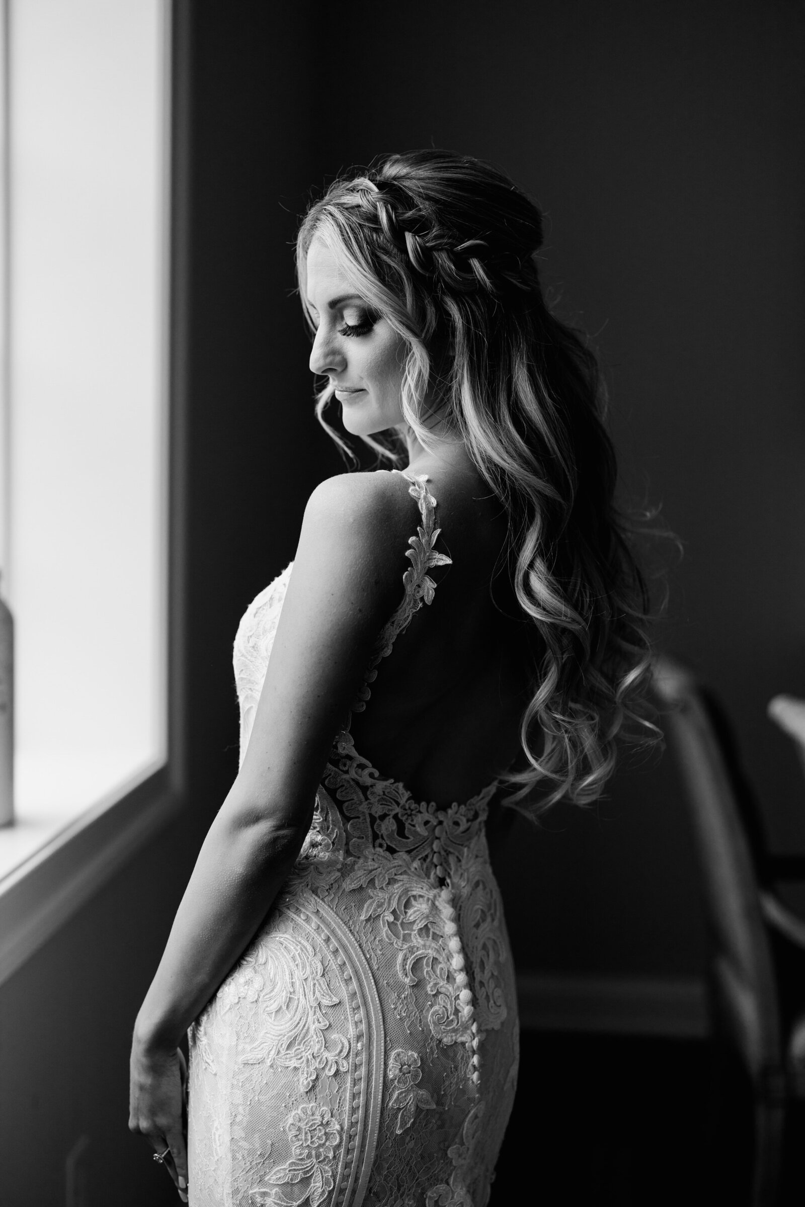 black and white image of bride lace dress at window