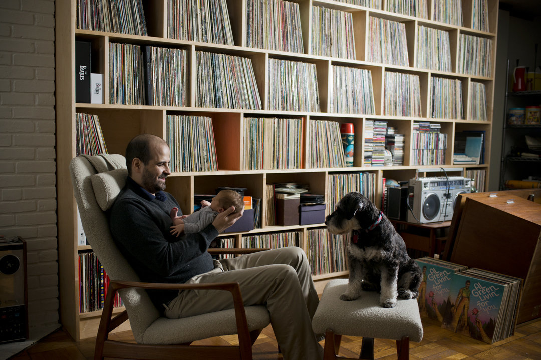 Father with record collection, holding newborn son.