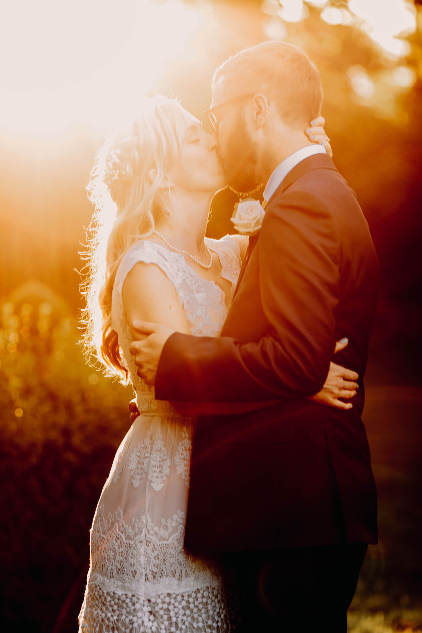 bride and groom kissing at sunset
