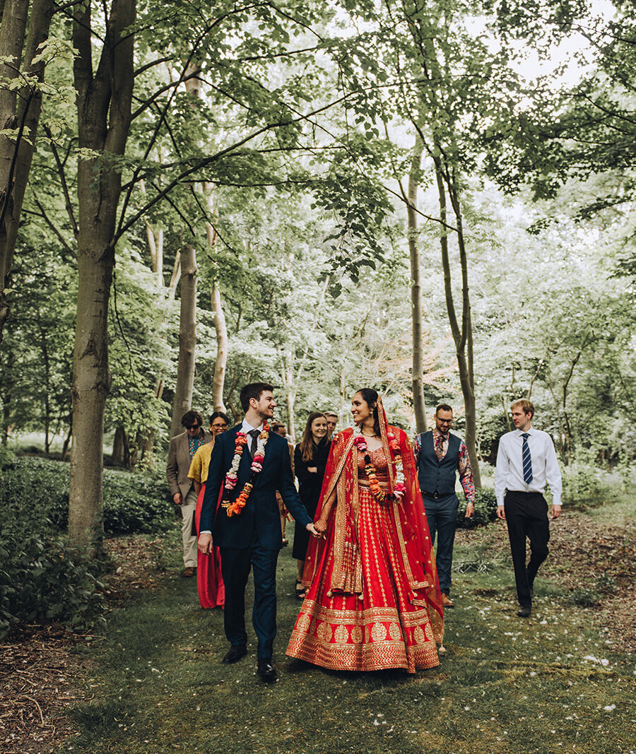 Indian bride and groom walking through a forest at their Cambridge wedding