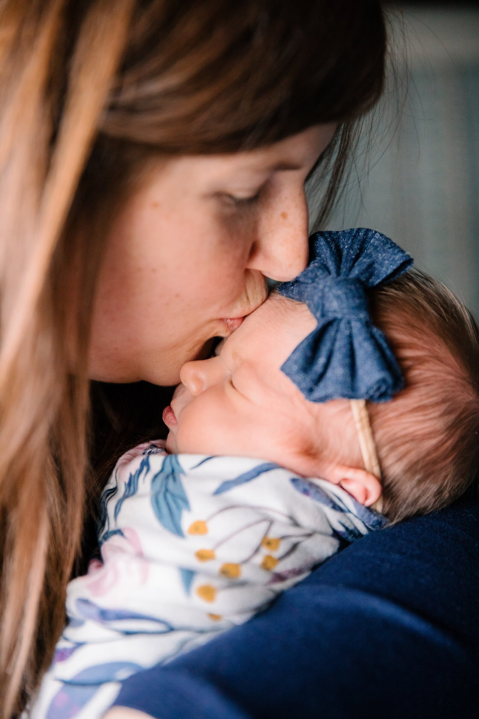 Newborn baby photo with mom kissing baby's forehead