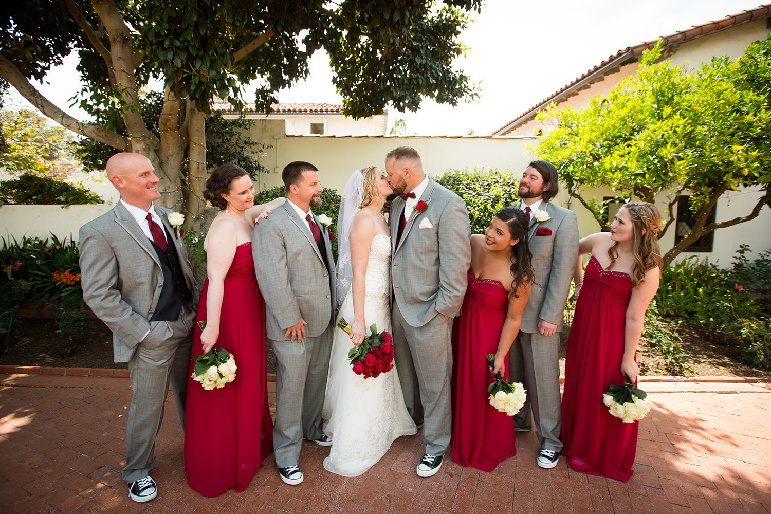 bridal party with red dresses and white flowers