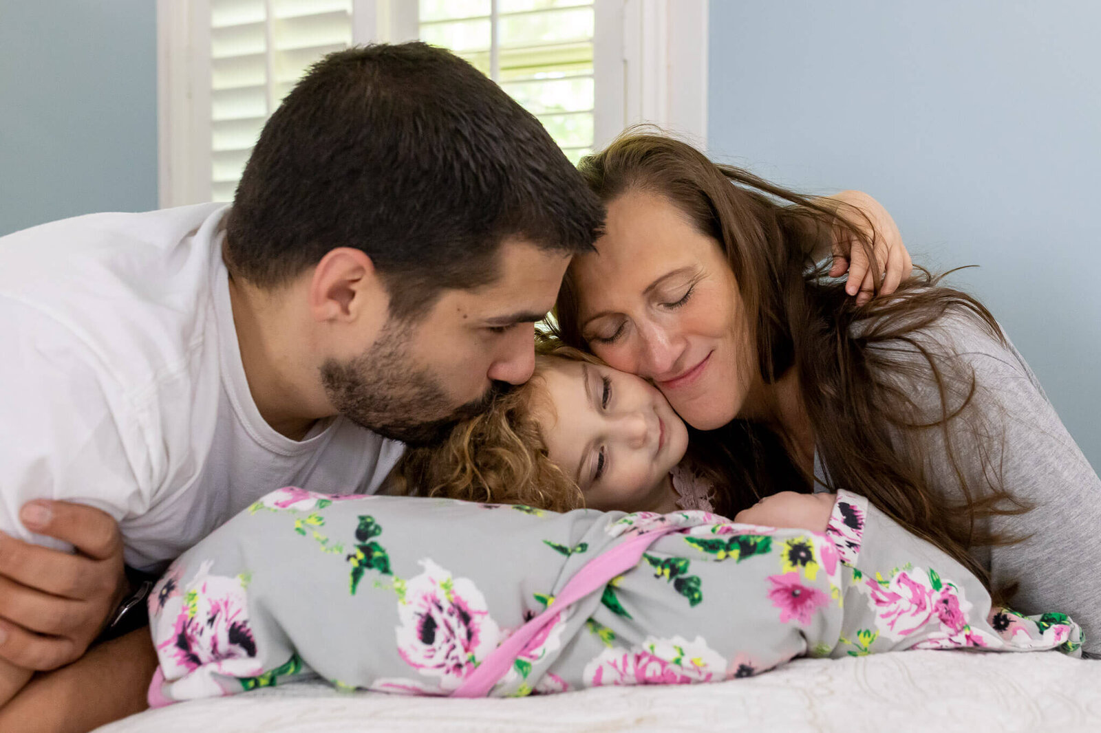 A family of four snuggling on the bed in their Alexandria home.