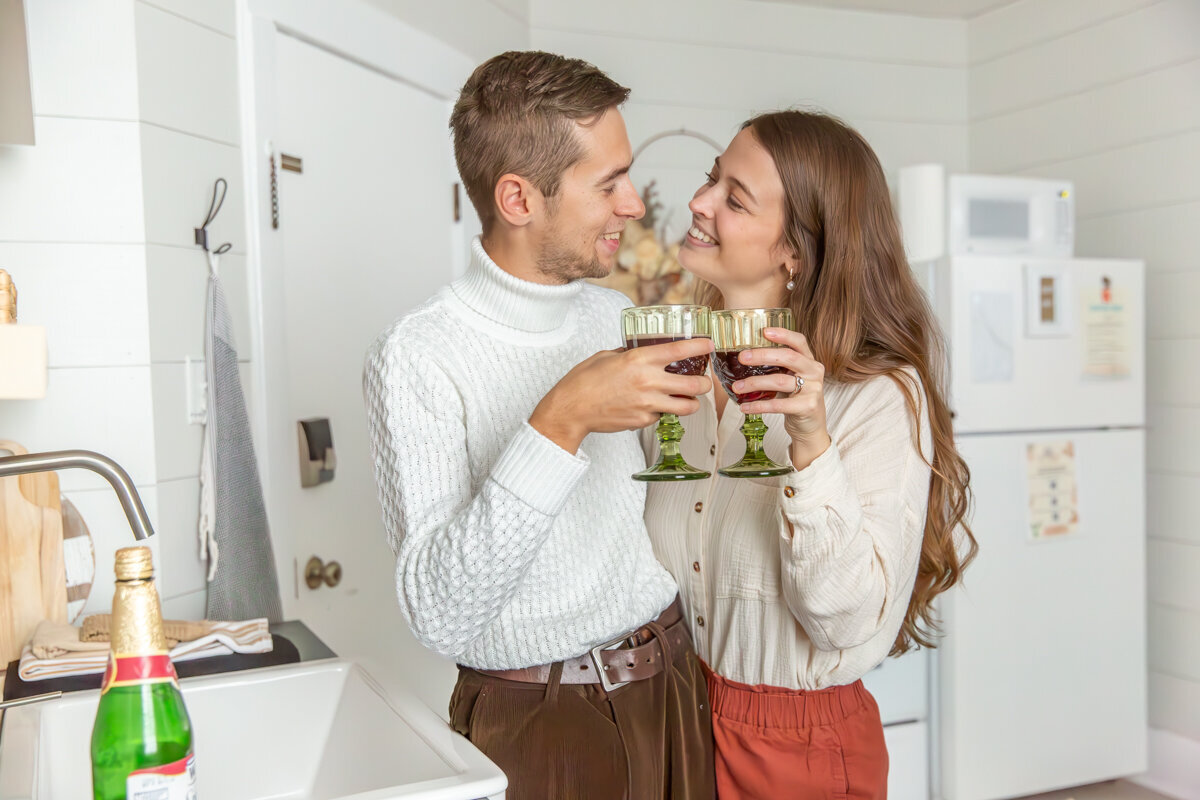 Couple cheering wine glasses in a kitchen at a branding photo session in sandusky, ohio
