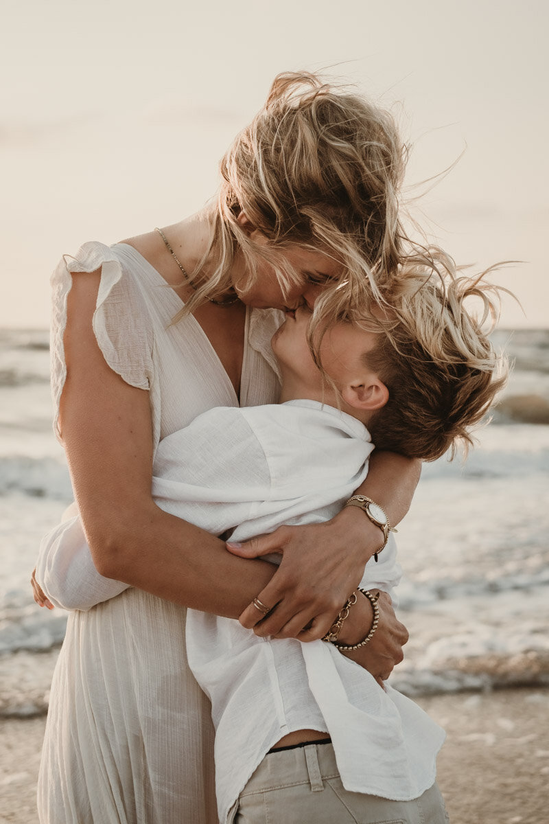 moeder en zoon knuffelend op het strand