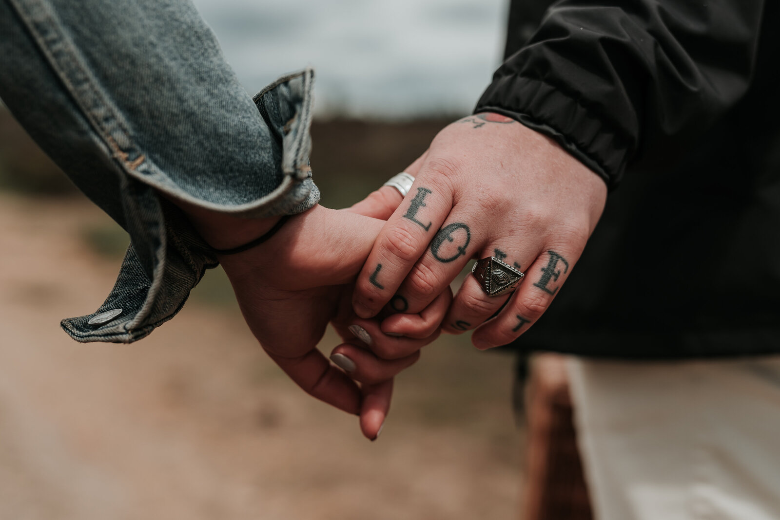 Close up of couple holding hands showing LOVE tattoo on man's fingers