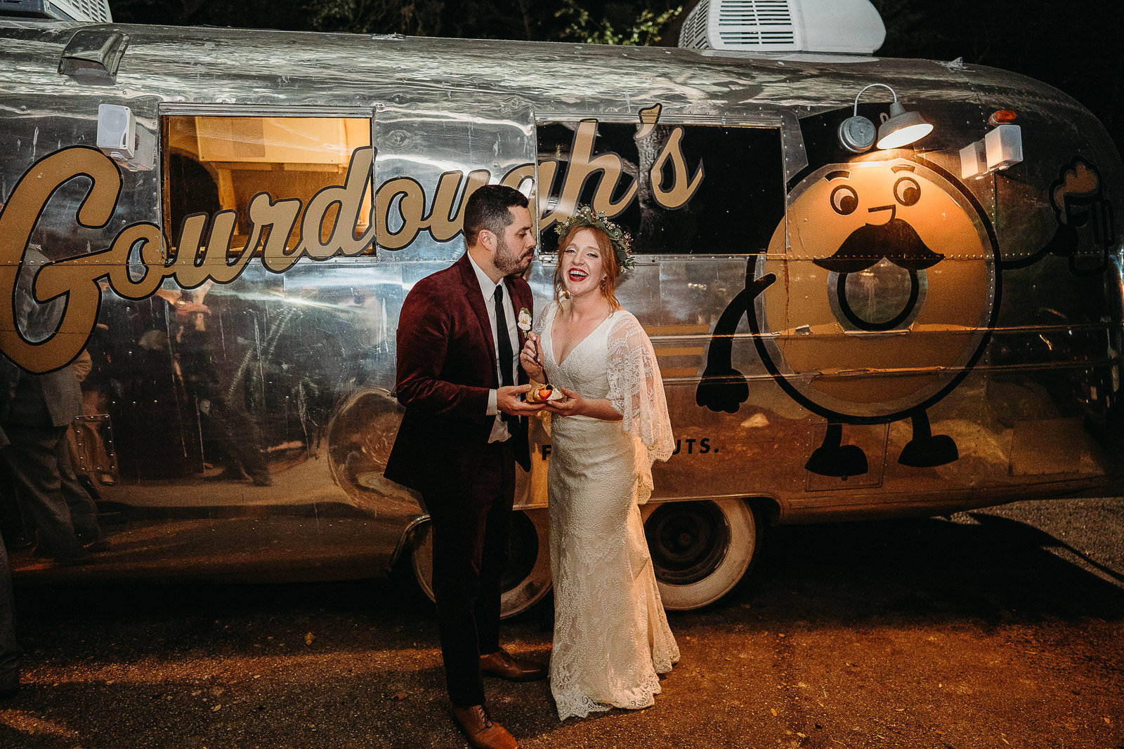 couple shares a donut outside food truck after wedding