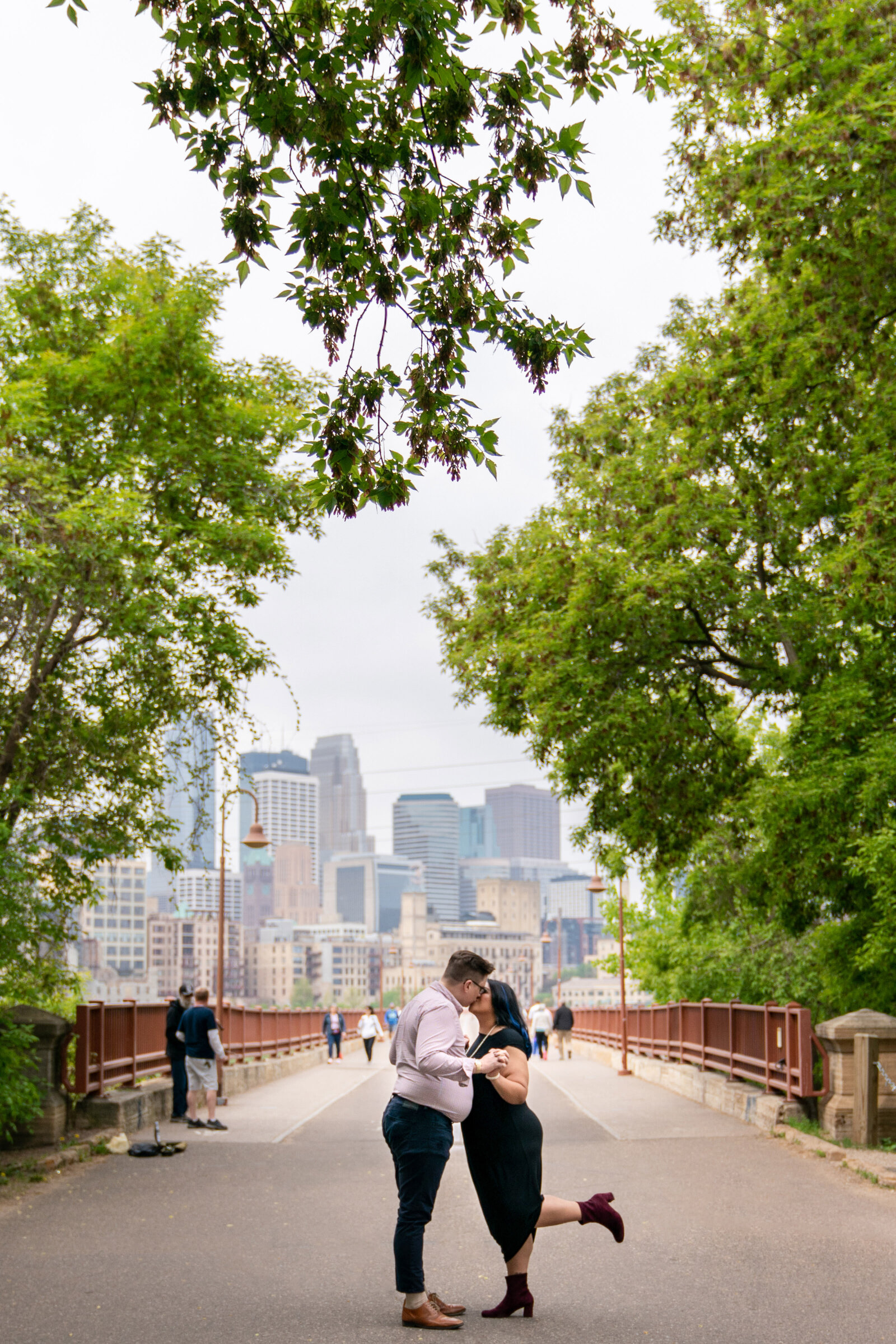 Man and woman kiss in front of the Stone Arch Bridge in Minneapolis, Minnesota.