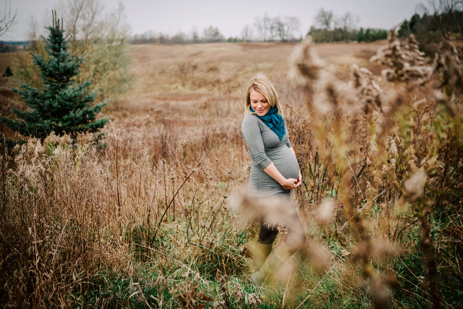 expecting mother holds her belly in a wheat field during November
