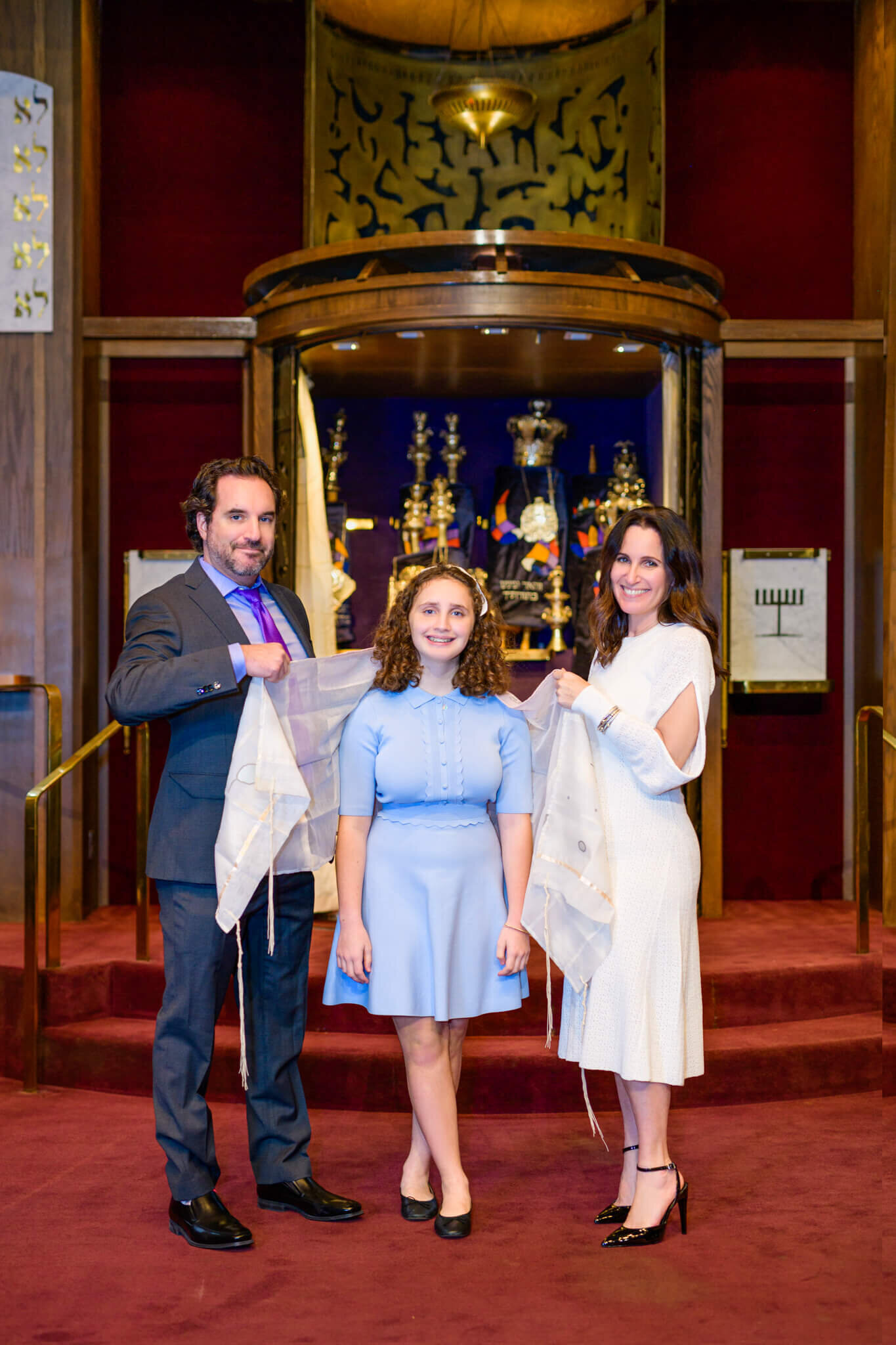 A mom and dad put the tallit on their daughter in the temple during their Bellevue Bar and Bat Mitzvah Photography session