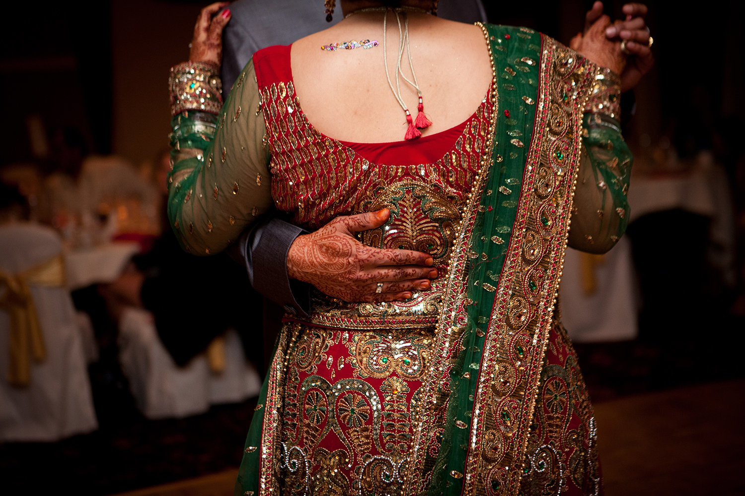 Romantic closeup of bride's sari and grooms hand during their first dance