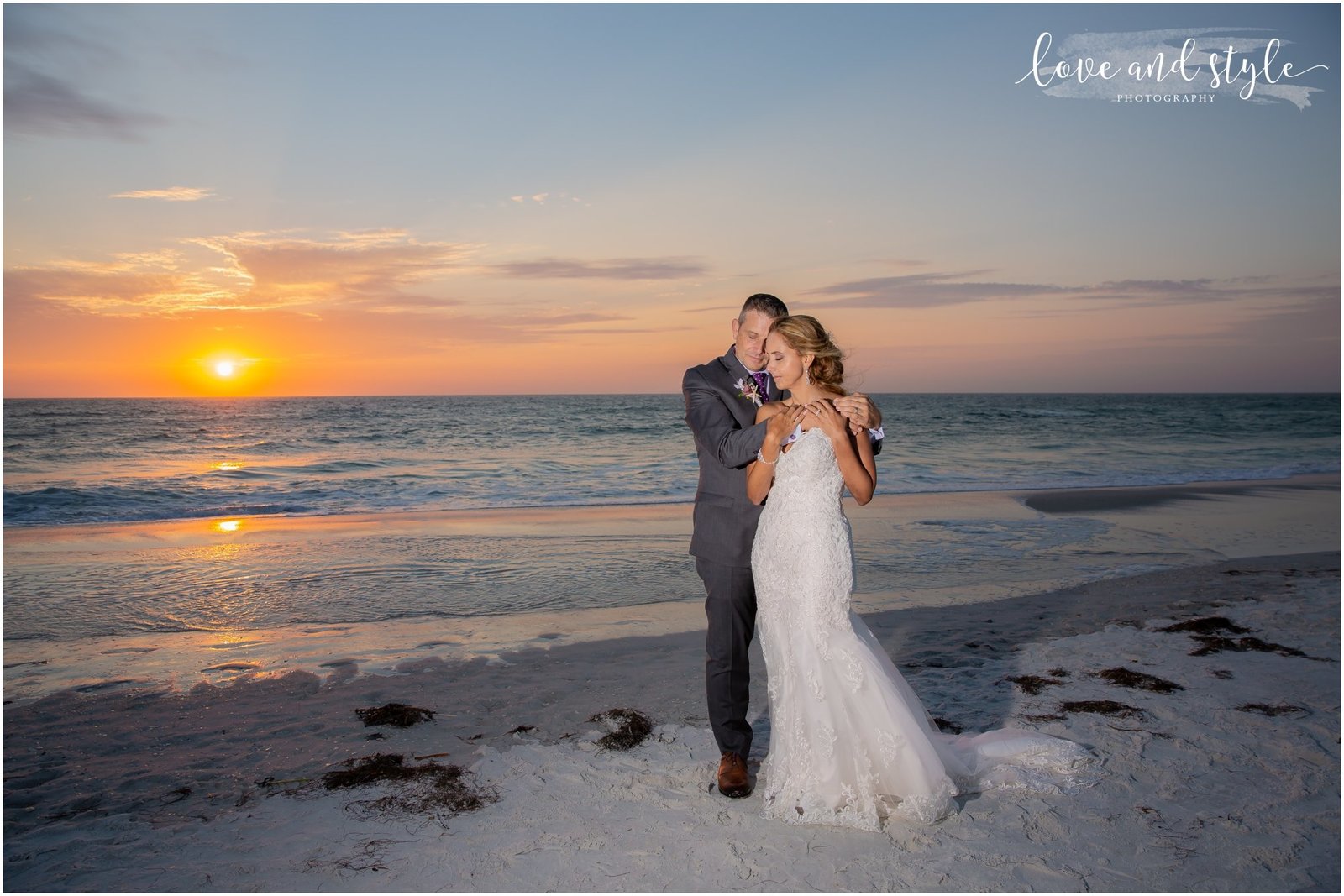 Bride and groom hugging at sunset on Bradenton Beach in front of The Beach House Restaurant