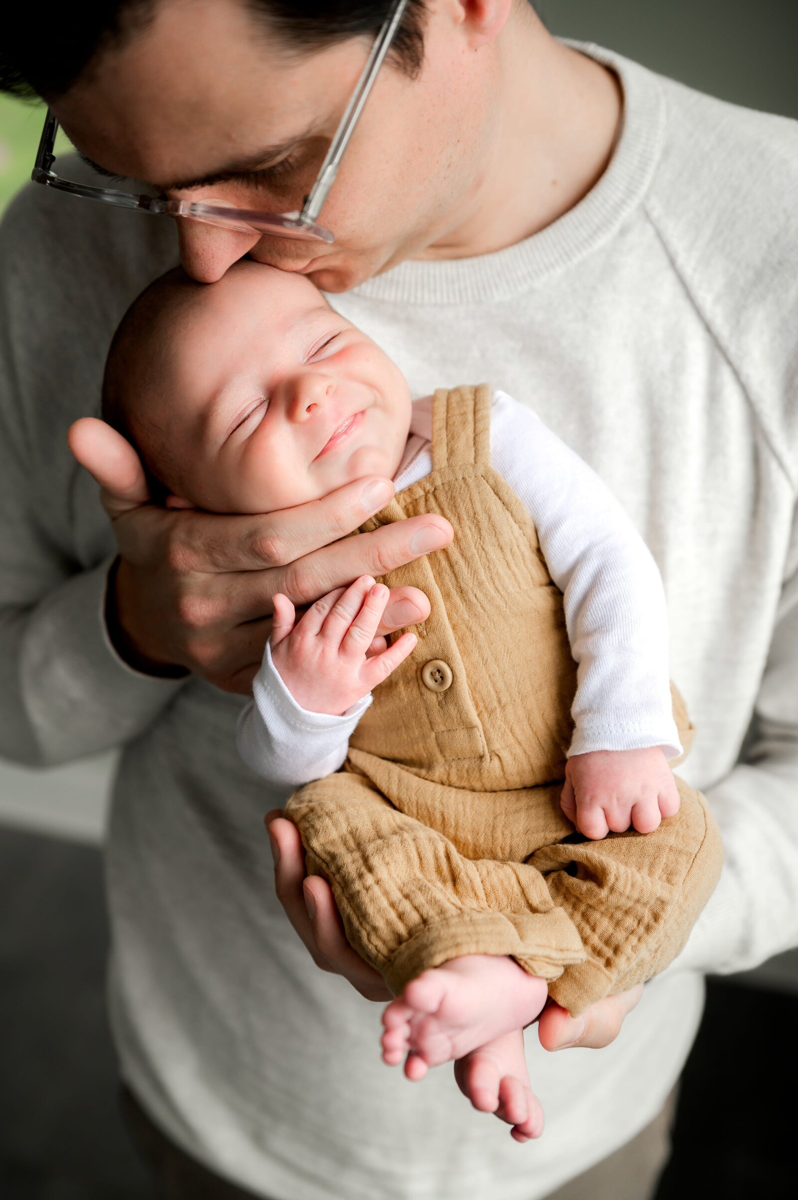 newborn boy smiling as das holding his hand